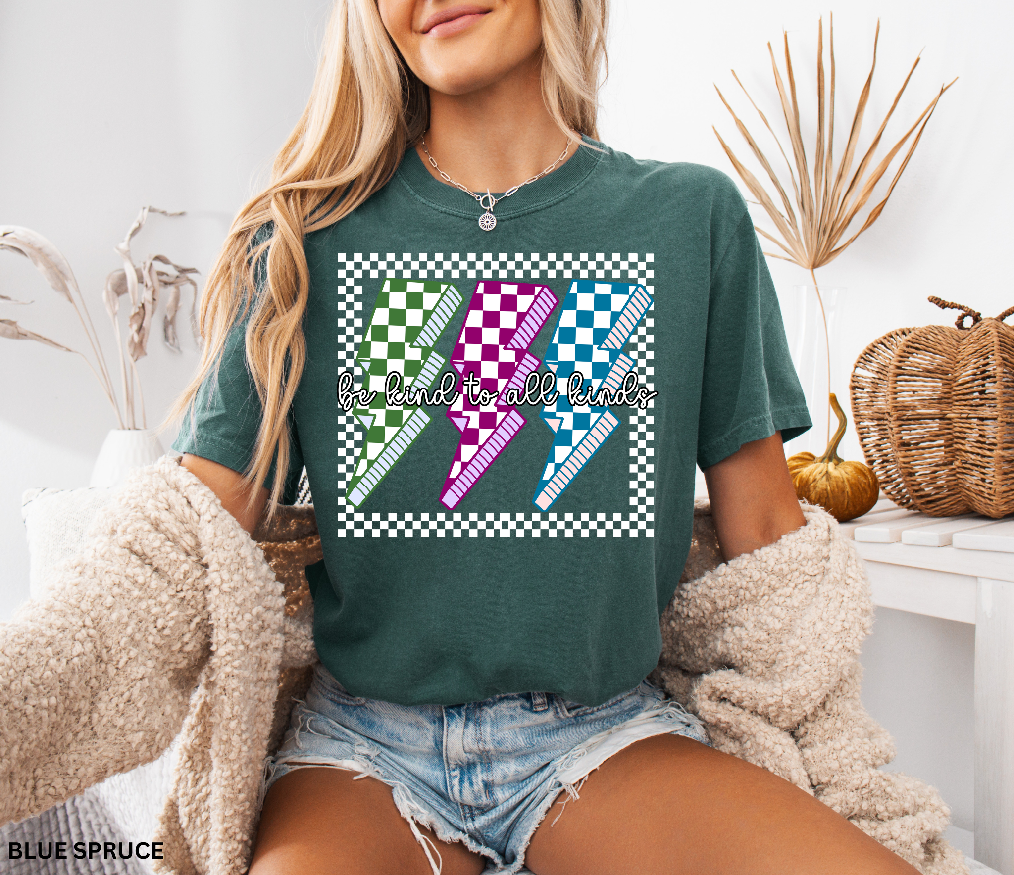 Checkerboard lightning bolt “Be Kind to All Kinds” shirt in retro green, pink, and blue design – inclusive teacher graphic tee.