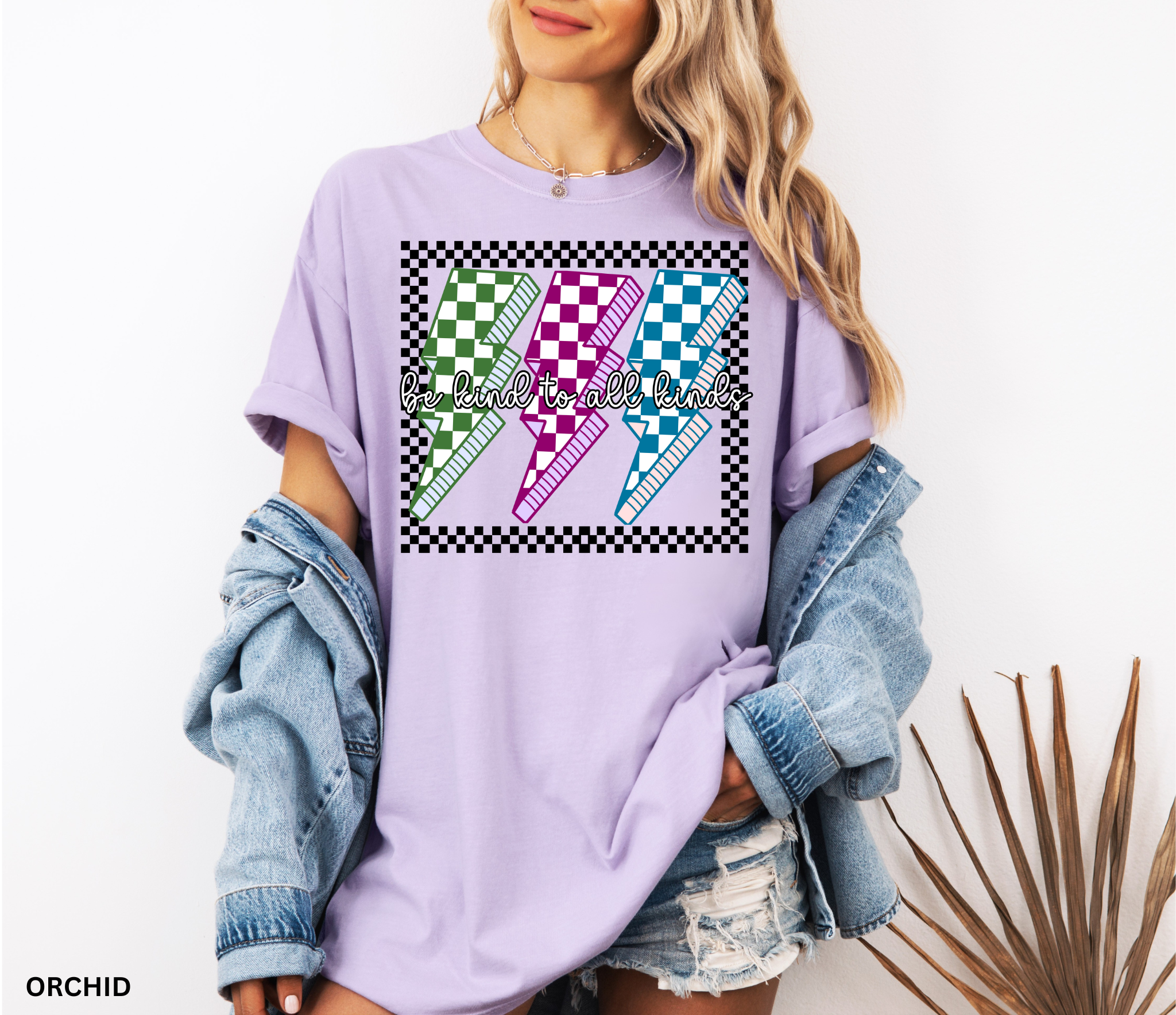 Checkerboard lightning bolt “Be Kind to All Kinds” shirt in retro green, pink, and blue design – inclusive teacher graphic tee.