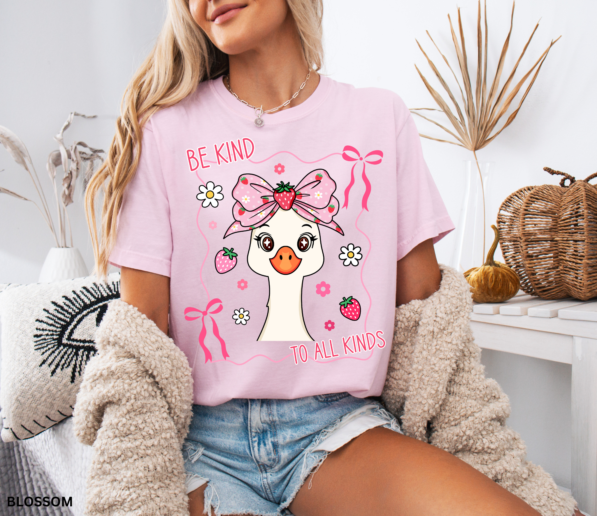 Goose with strawberry bow and flowers framed in ribbons with the phrase “Be Kind to All Kinds.”