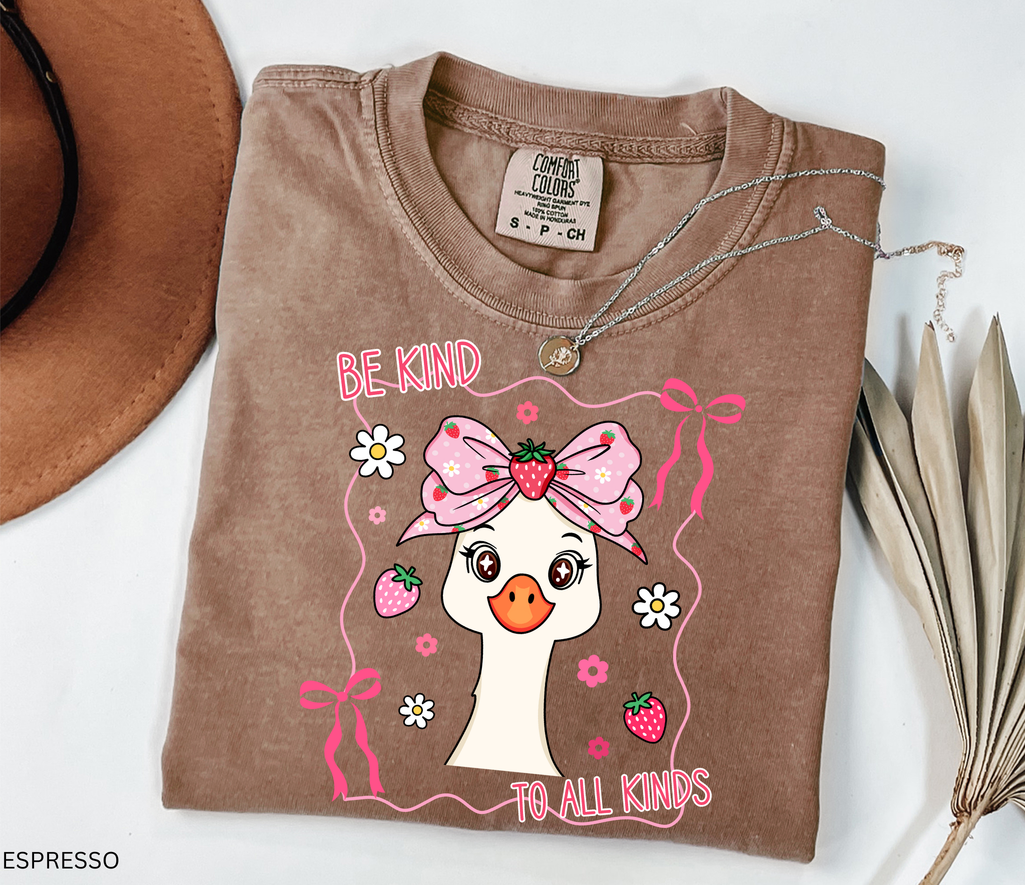 Goose with strawberry bow and flowers framed in ribbons with the phrase “Be Kind to All Kinds.”
