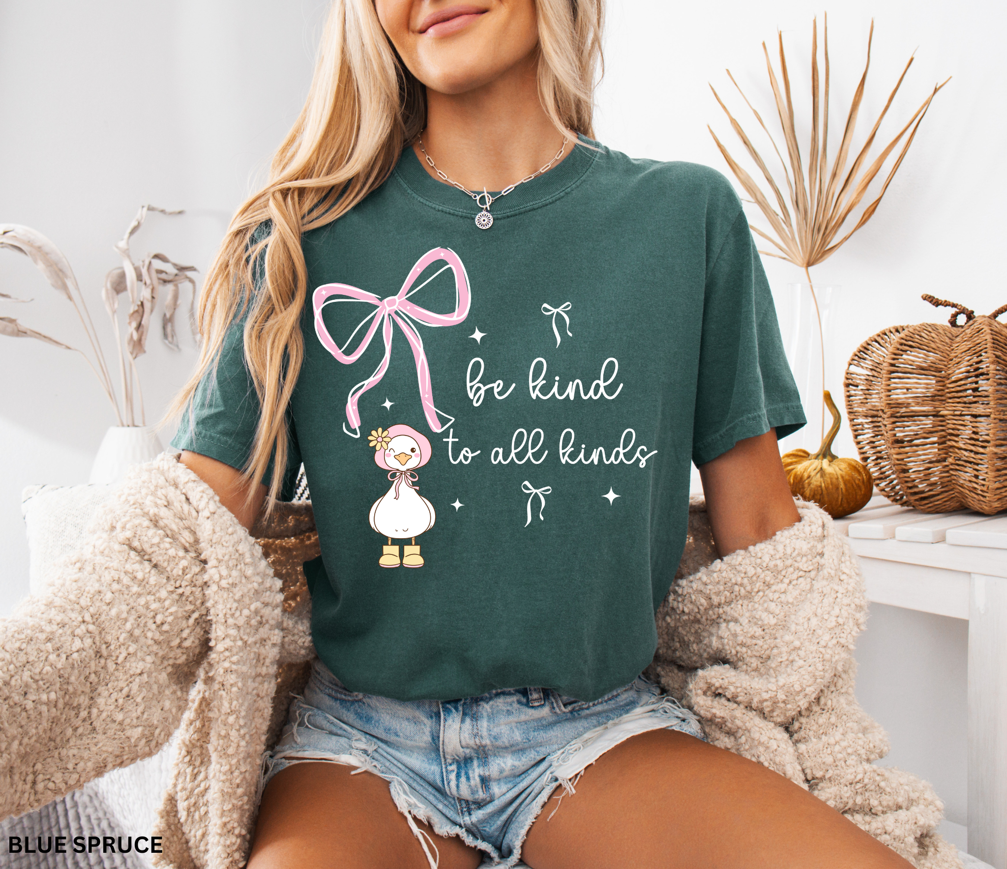 Cute goose wearing a pink bonnet with flower and boots, large pink bow above, and the words “Be Kind to All Kinds.”