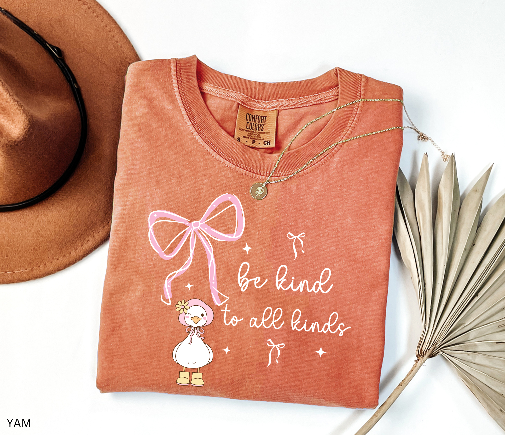 Cute goose wearing a pink bonnet with flower and boots, large pink bow above, and the words “Be Kind to All Kinds.”