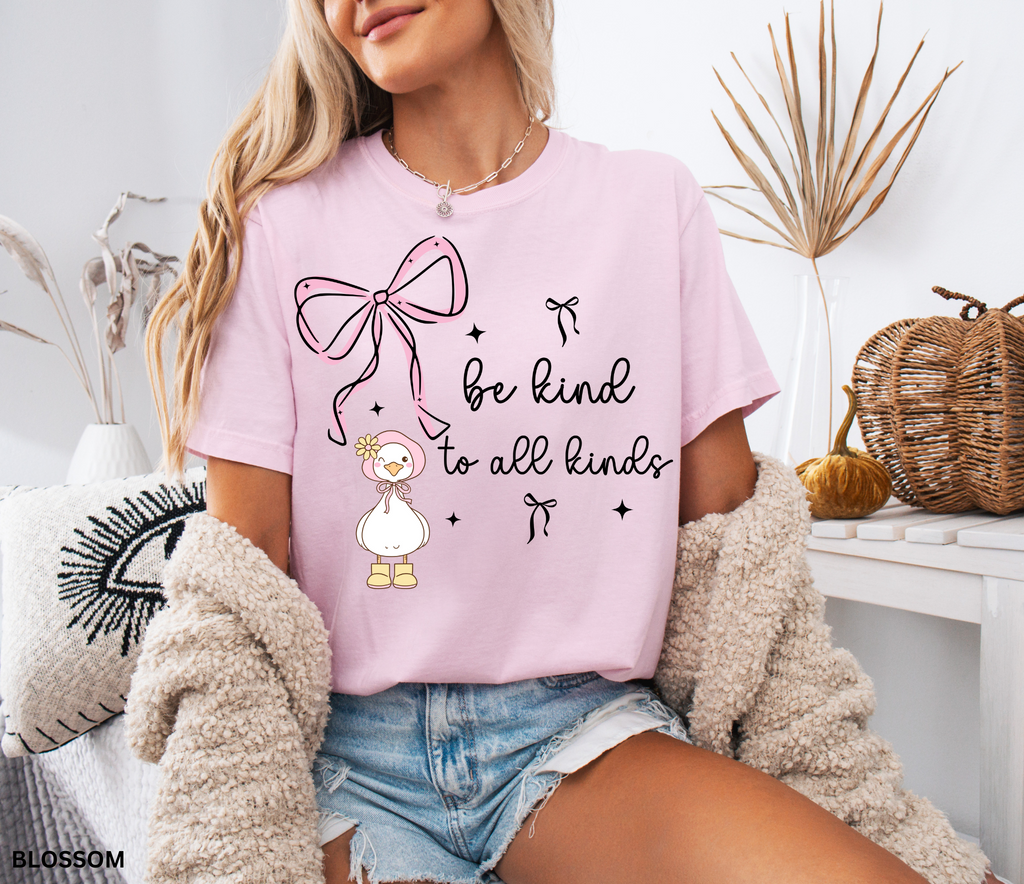 Cute goose wearing a pink bonnet with flower and boots, large pink bow above, and the words “Be Kind to All Kinds.”