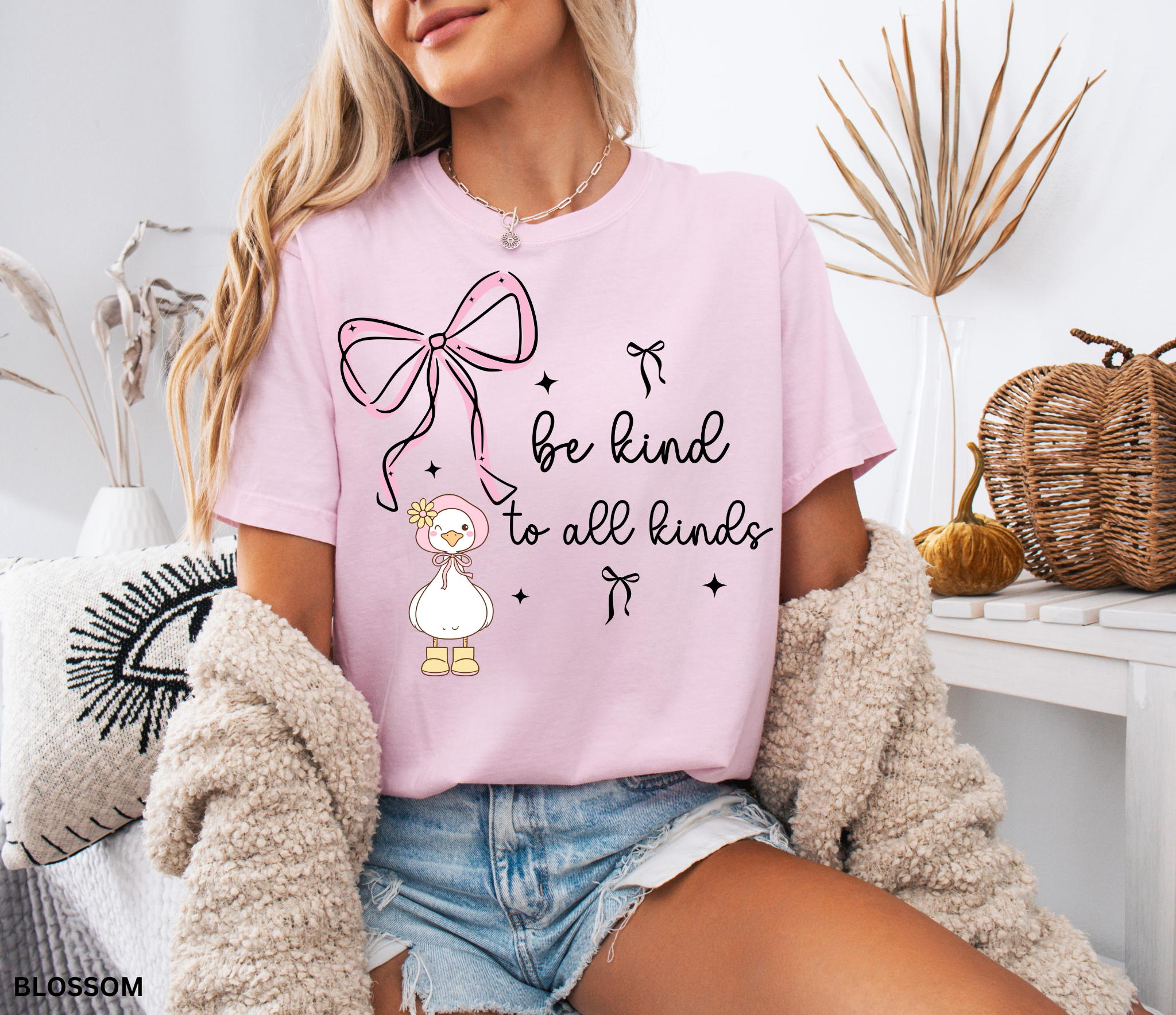 Cute goose wearing a pink bonnet with flower and boots, large pink bow above, and the words “Be Kind to All Kinds.”