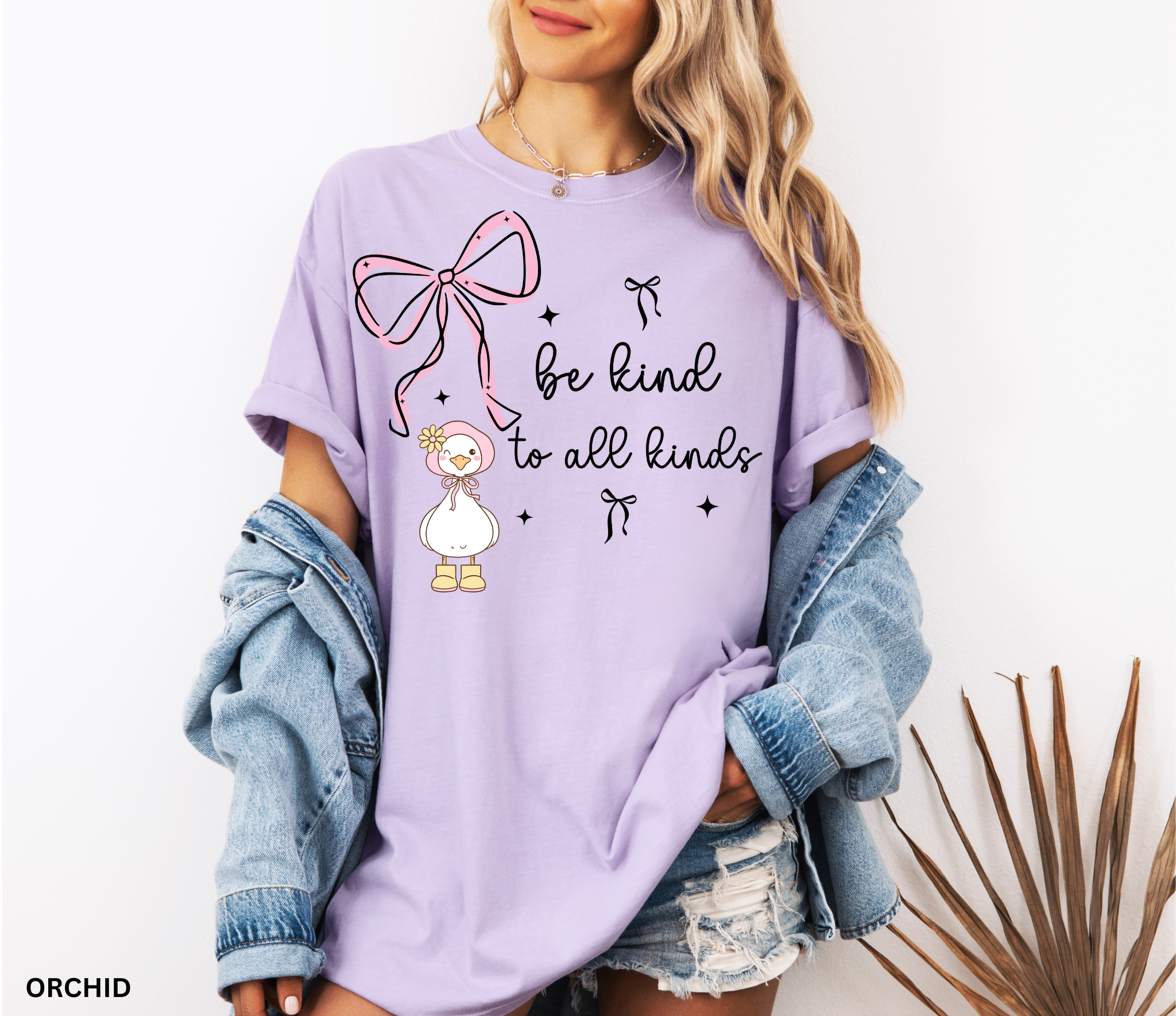 Cute goose wearing a pink bonnet with flower and boots, large pink bow above, and the words “Be Kind to All Kinds.”