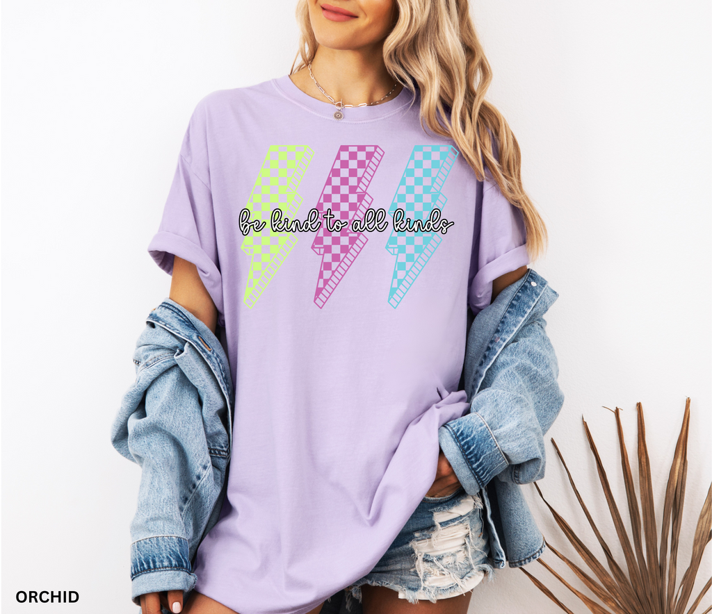 Three retro lightning bolts in neon green, pink, and blue checkered patterns with the phrase “Be Kind to All Kinds.”
