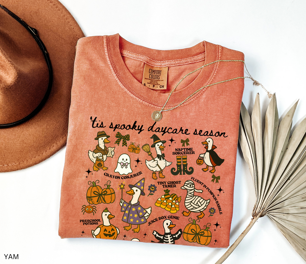 Halloween daycare teacher shirt with geese dressed in spooky costumes and playful phrases like ’Tis Spooky Daycare Season, Crayon Conjurer, and Juice Box Genie.