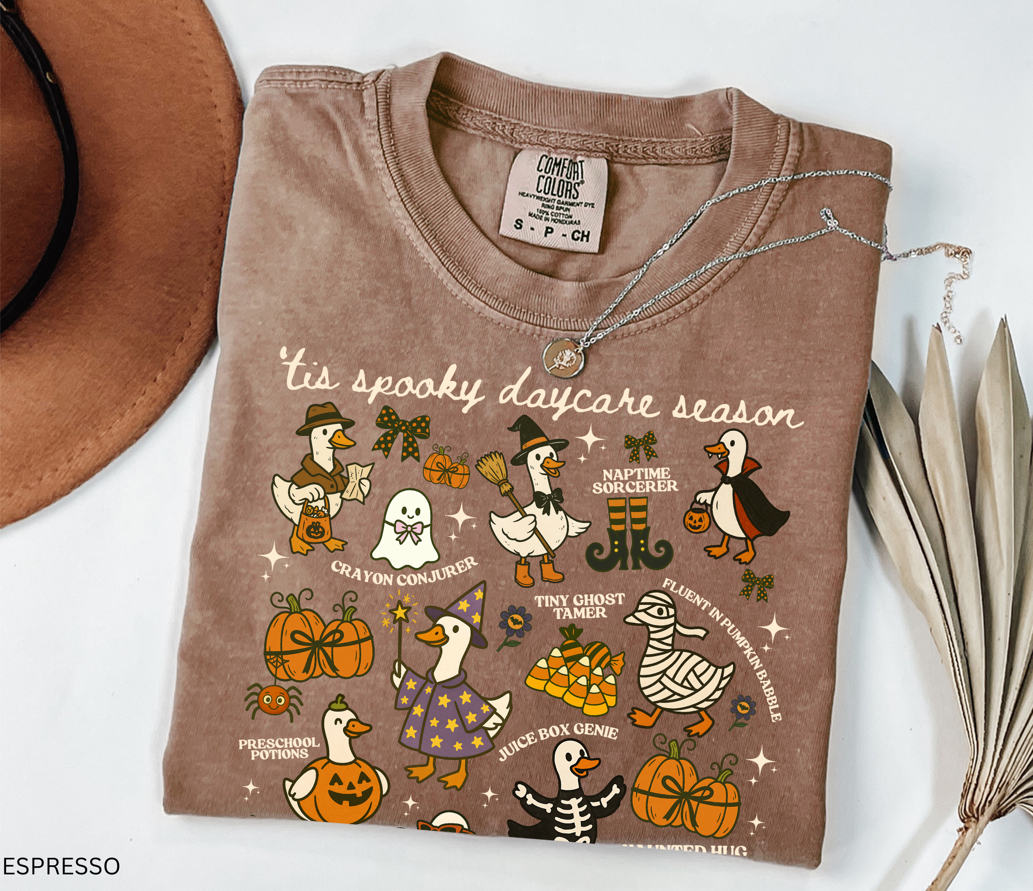 Halloween daycare teacher shirt with geese dressed in spooky costumes and playful phrases like ’Tis Spooky Daycare Season, Crayon Conjurer, and Juice Box Genie.