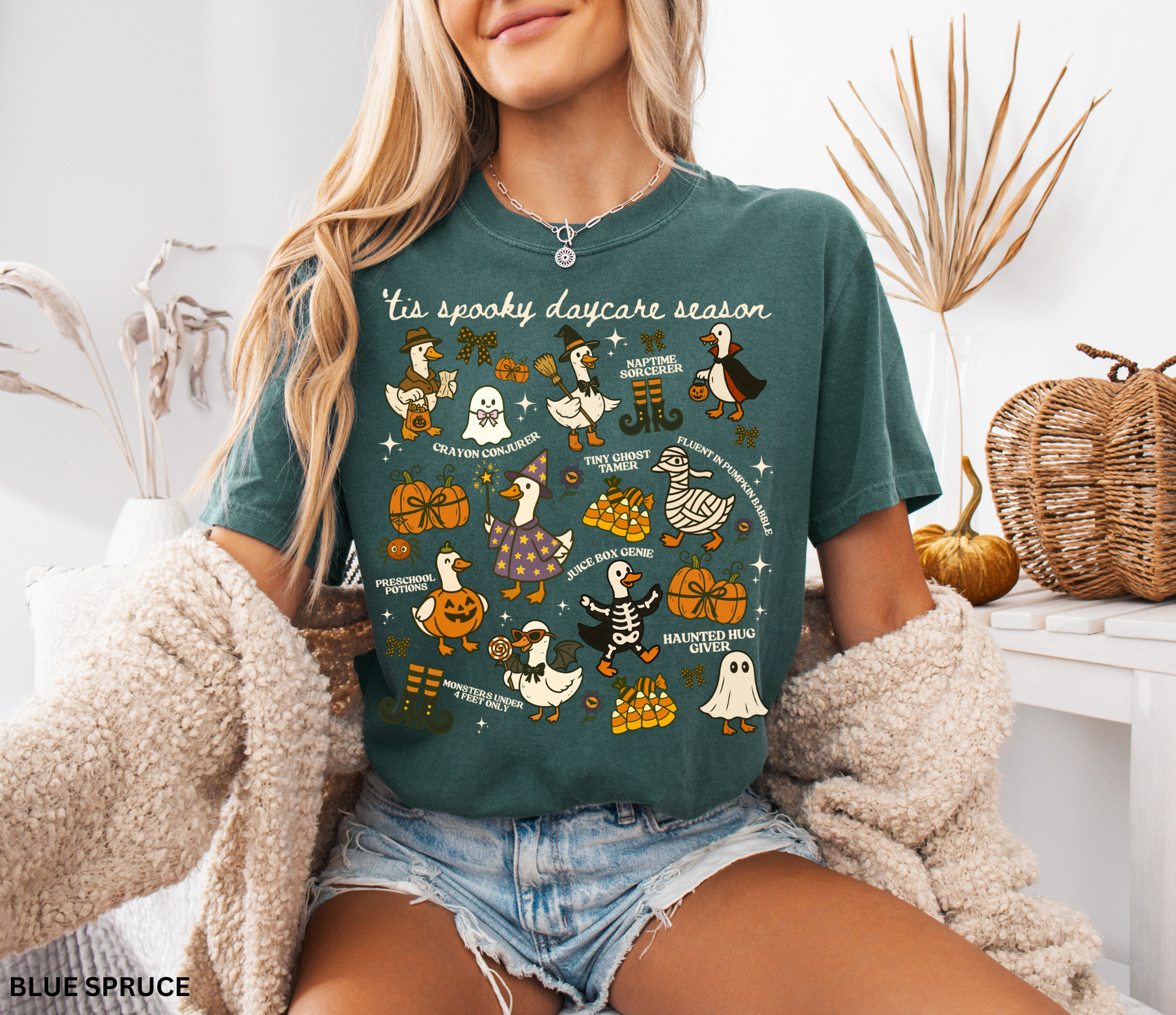 “Halloween daycare teacher shirt with geese dressed in spooky costumes and playful phrases like ’Tis Spooky Daycare Season, Crayon Conjurer, and Juice Box Genie.