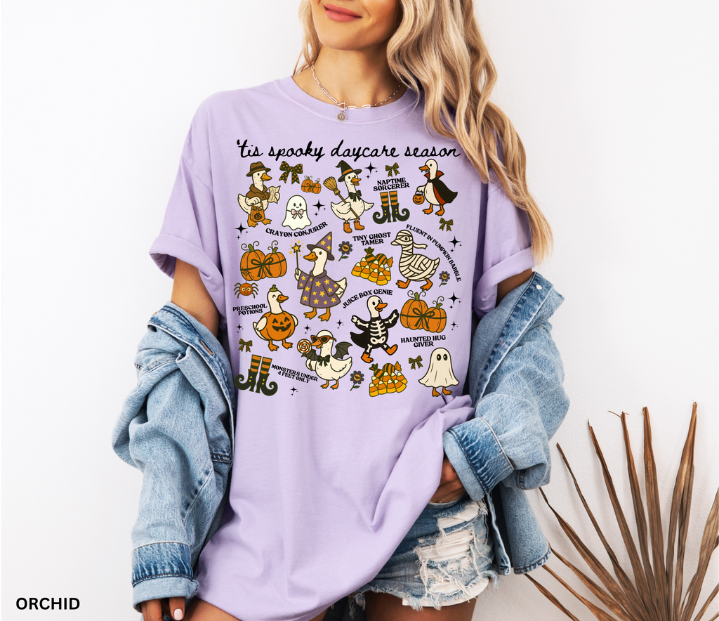 Halloween daycare teacher shirt with geese dressed in spooky costumes and playful phrases like ’Tis Spooky Daycare Season, Crayon Conjurer, and Juice Box Genie.