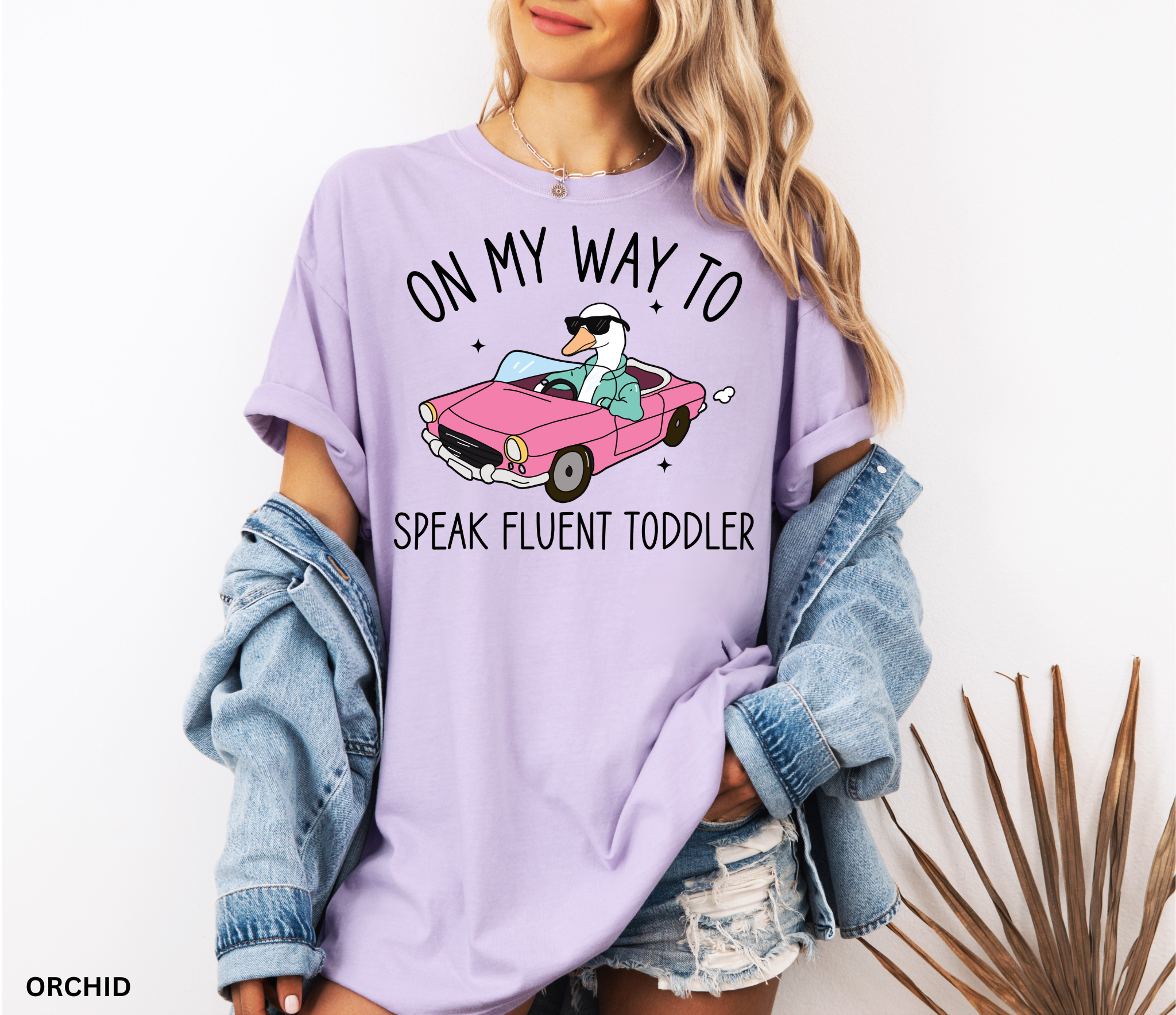 Daycare teacher shirt with a goose driving a pink convertible wearing sunglasses and the phrase ‘On My Way to Speak Fluent Toddler.