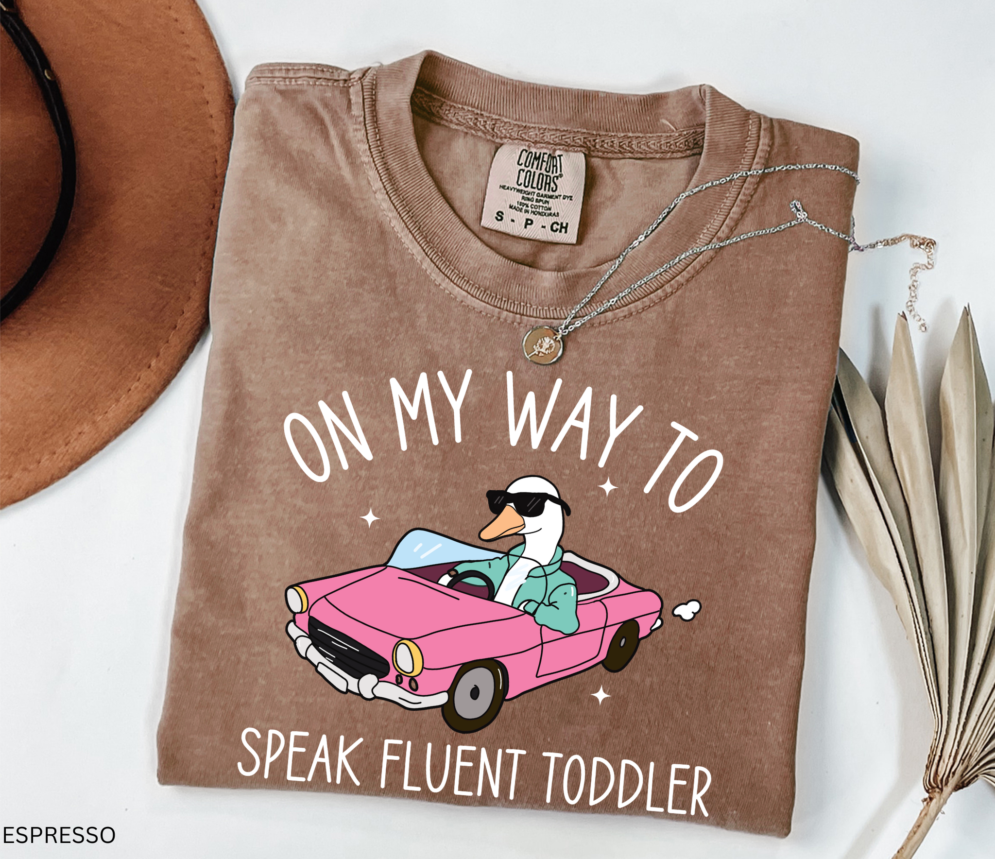 Daycare teacher shirt with a goose driving a pink convertible wearing sunglasses and the phrase ‘On My Way to Speak Fluent Toddler.