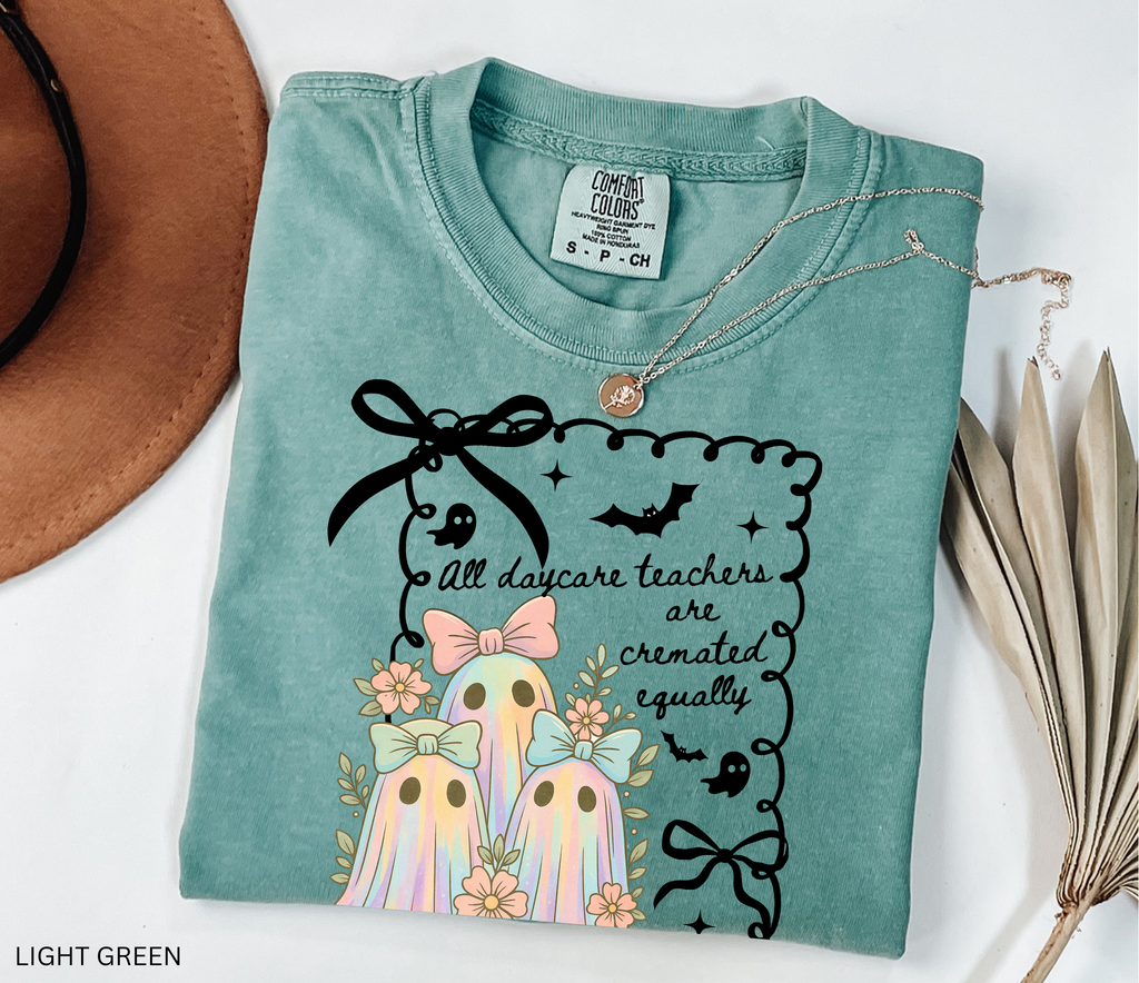 Halloween daycare teacher shirt with three pastel rainbow ghosts wearing bows, surrounded by flowers. Cute and spooky teacher tee for childcare staff.