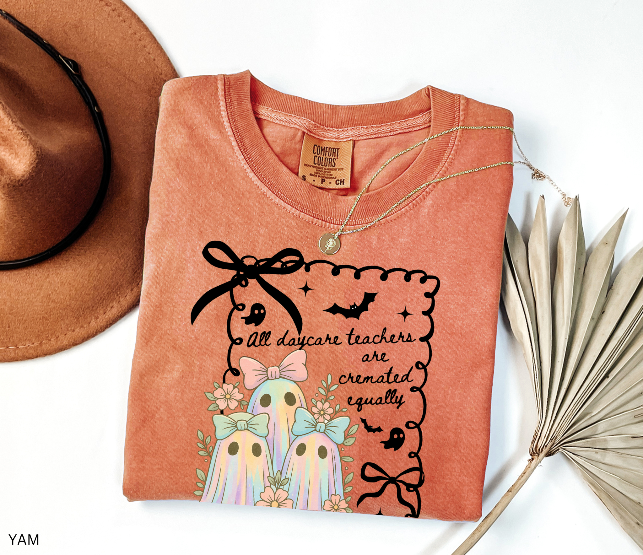 Halloween daycare teacher shirt with three pastel rainbow ghosts wearing bows, surrounded by flowers. Cute and spooky teacher tee for childcare staff.