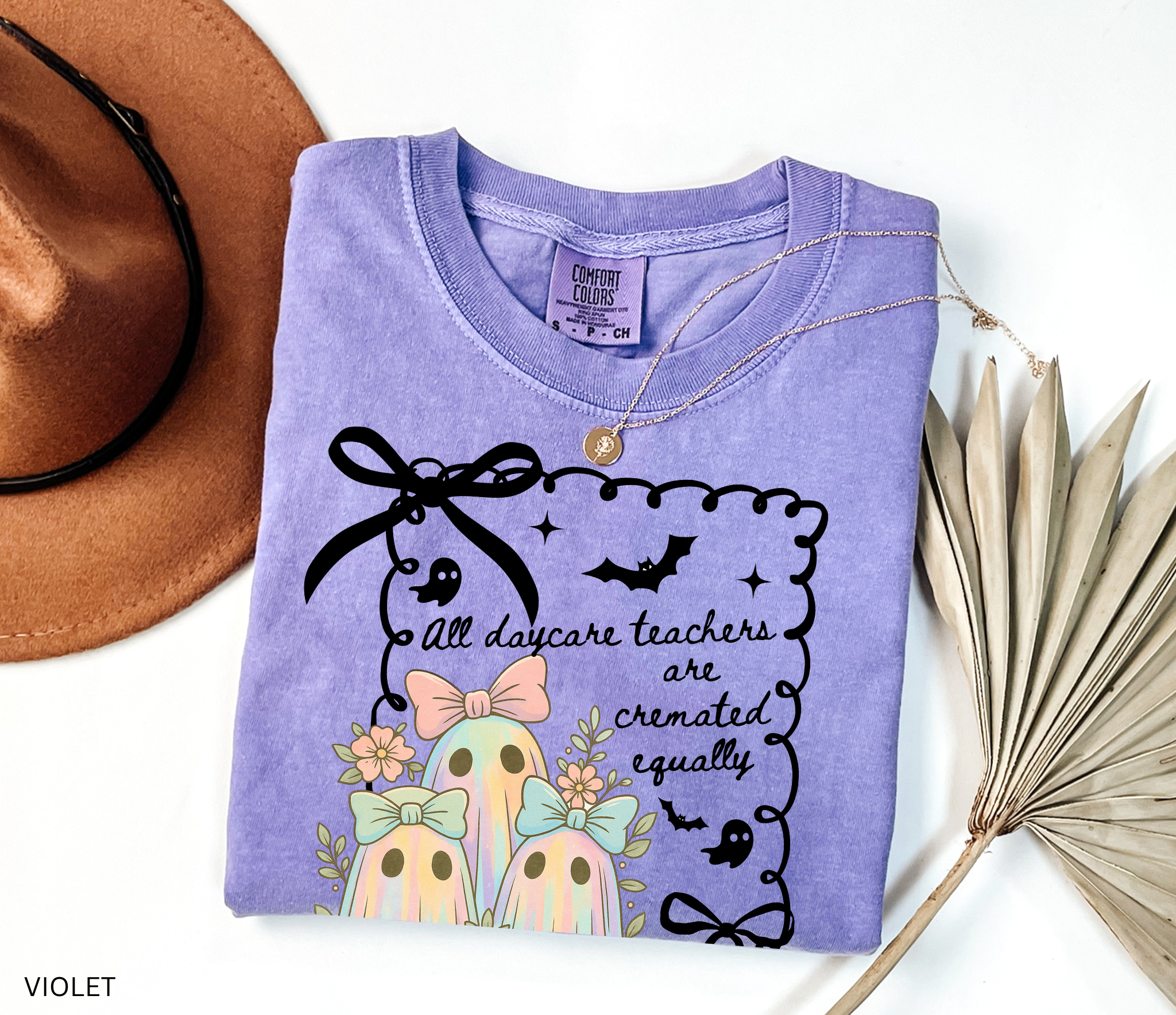 Halloween daycare teacher shirt with three pastel rainbow ghosts wearing bows, surrounded by flowers. Cute and spooky teacher tee for childcare staff.