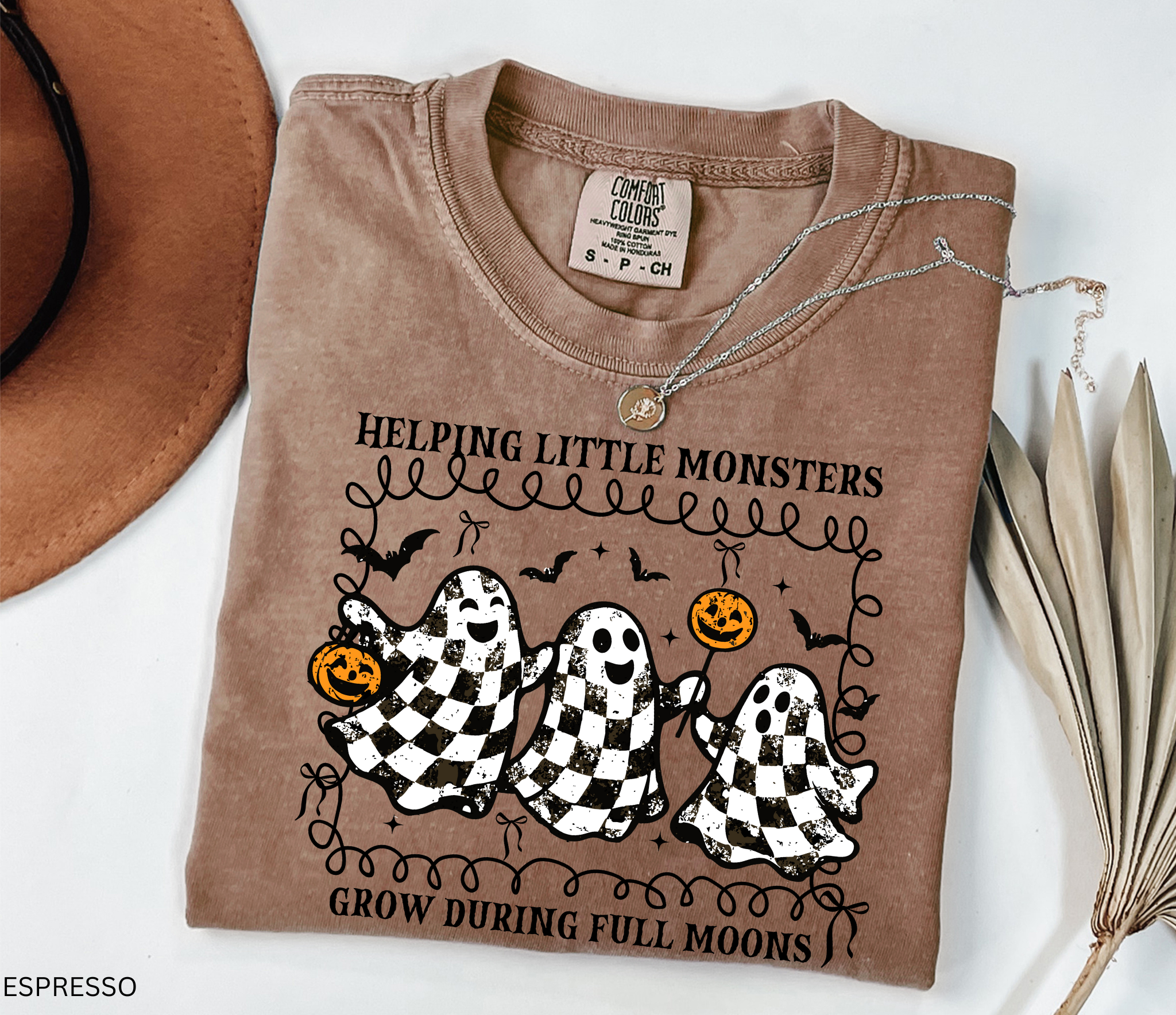 Halloween daycare teacher shirt with three checkered black-and-white ghosts holding pumpkins and lollipops, surrounded by bats. Cute spooky tee