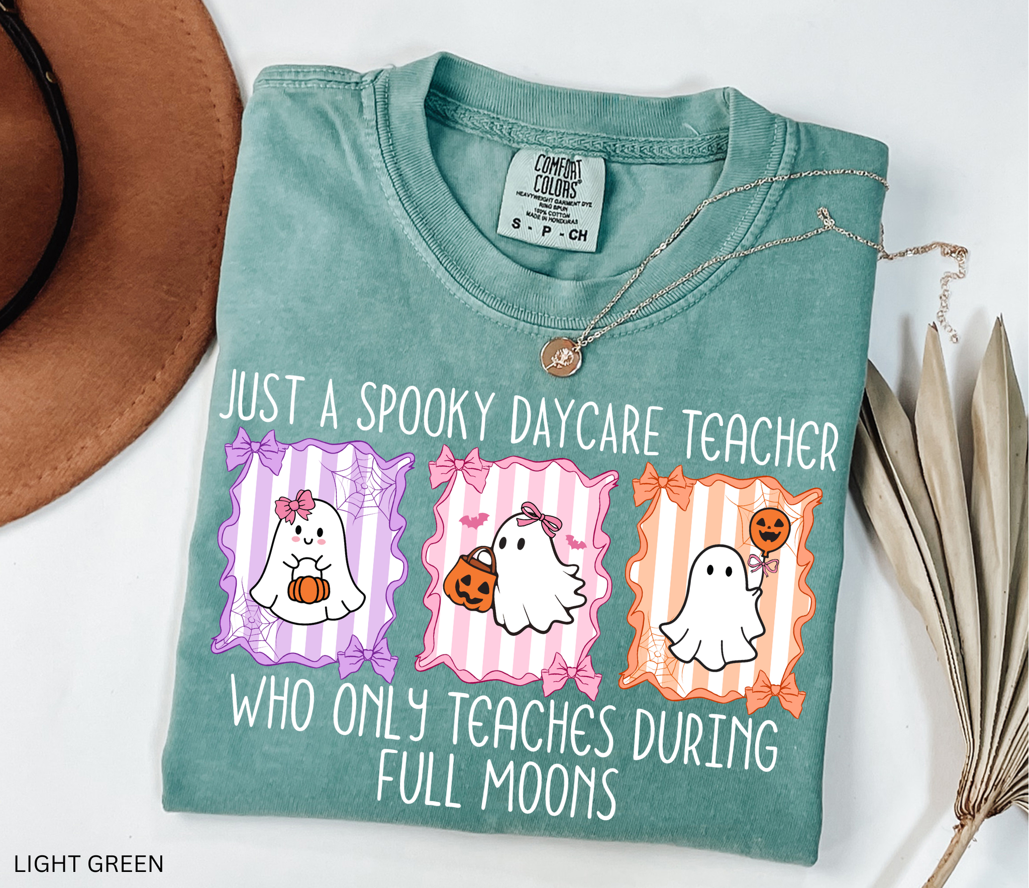 Halloween daycare teacher shirt with three pastel ghosts holding pumpkins, framed with bows and spiderwebs. Text says Just a spooky daycare teacher who only teaches during full moons.