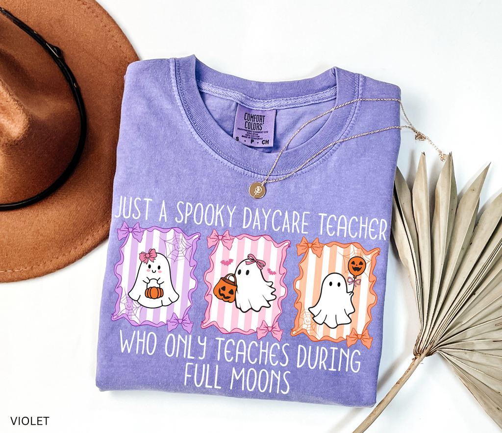 Halloween daycare teacher shirt with three pastel ghosts holding pumpkins, framed with bows and spiderwebs. Text says Just a spooky daycare teacher who only teaches during full moons.