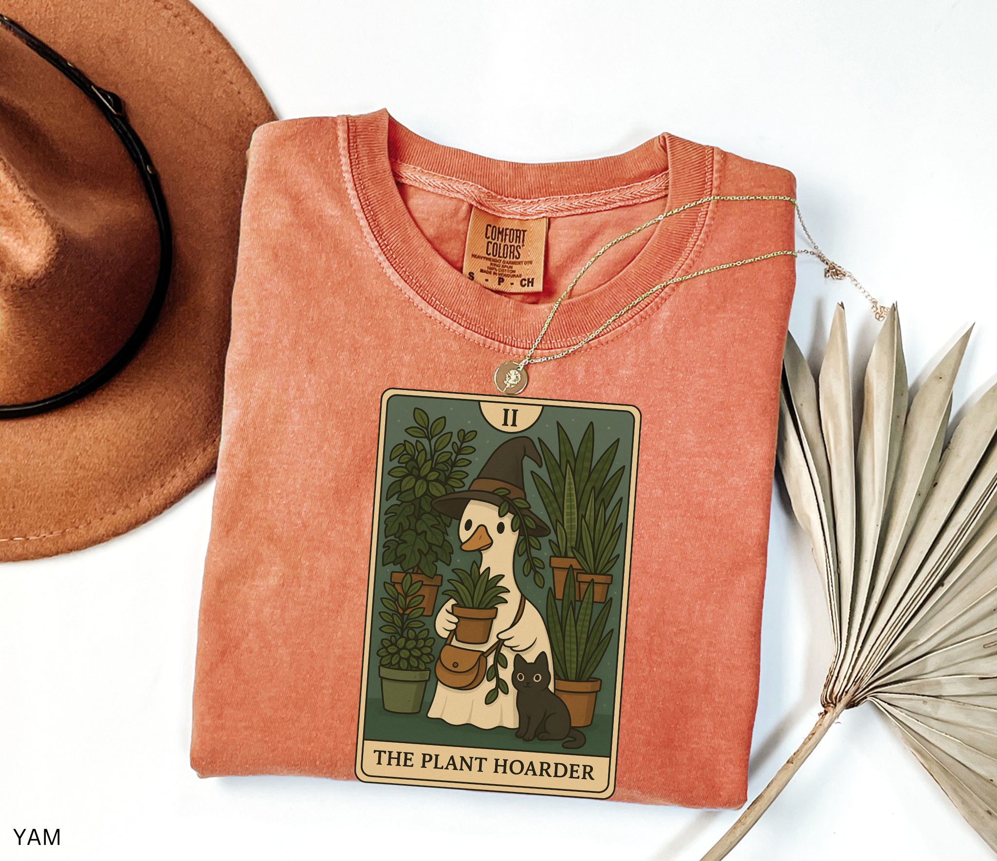 Witchy plant hoarder shirt featuring a tarot card design of a goose in a witch hat holding plants, surrounded by greenery and a black cat.