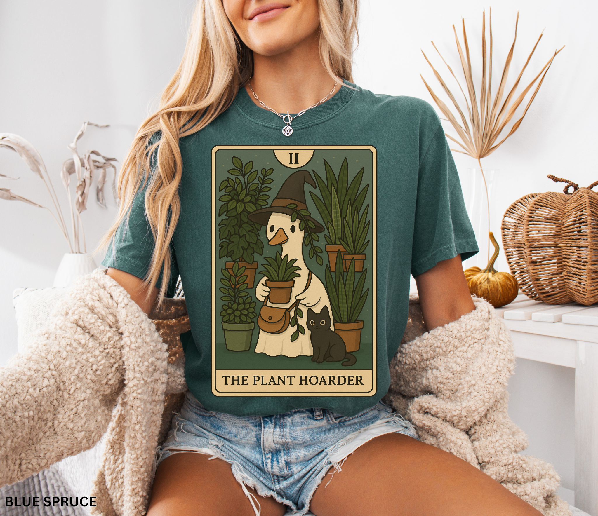 Witchy plant hoarder shirt featuring a tarot card design of a goose in a witch hat holding plants, surrounded by greenery and a black cat.