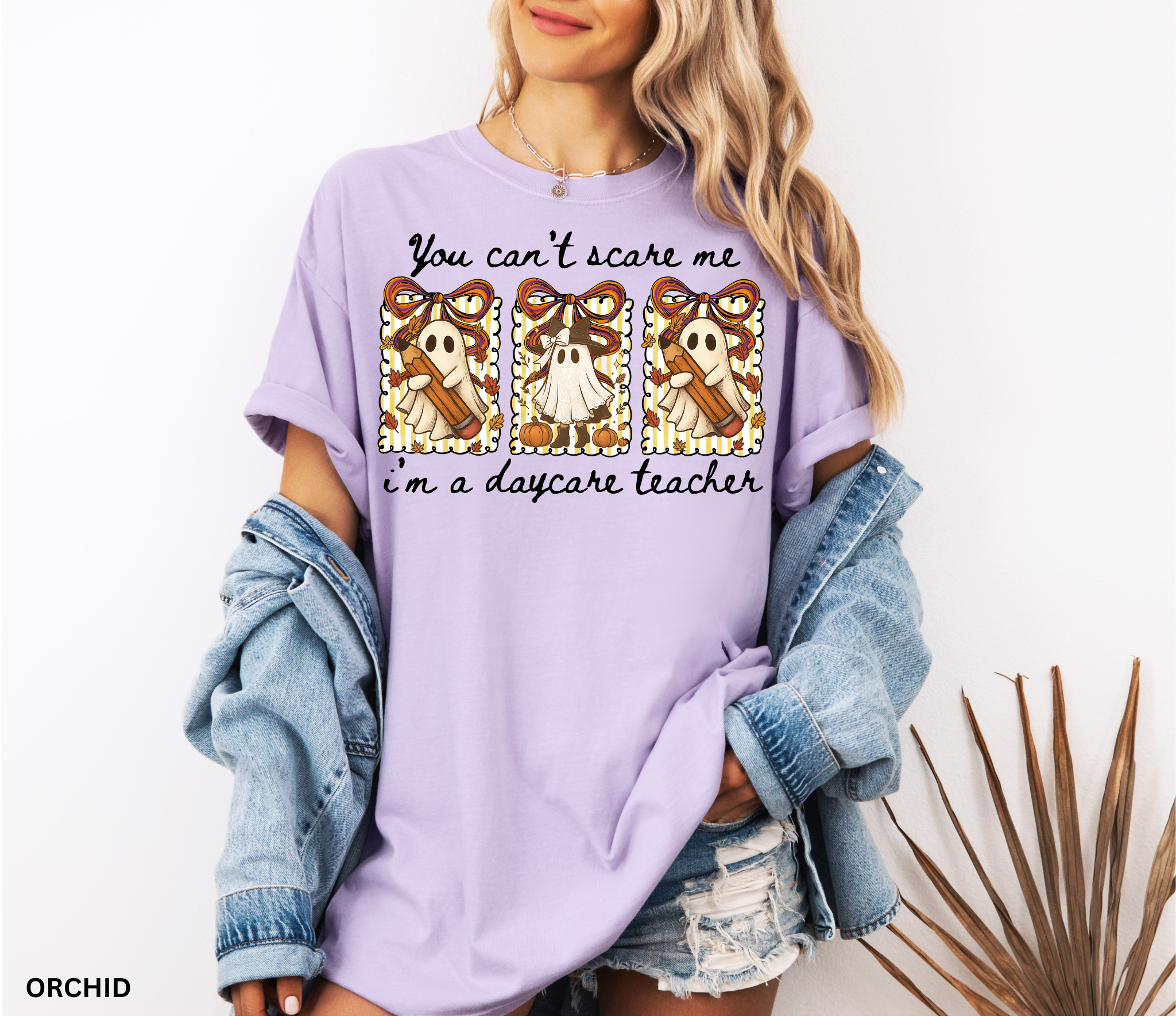 Halloween daycare teacher shirt with three cute ghosts holding pencils and pumpkins, decorated with striped backgrounds, bows, and the phrase “You Can’t Scare Me, I’m a Daycare Teacher.”