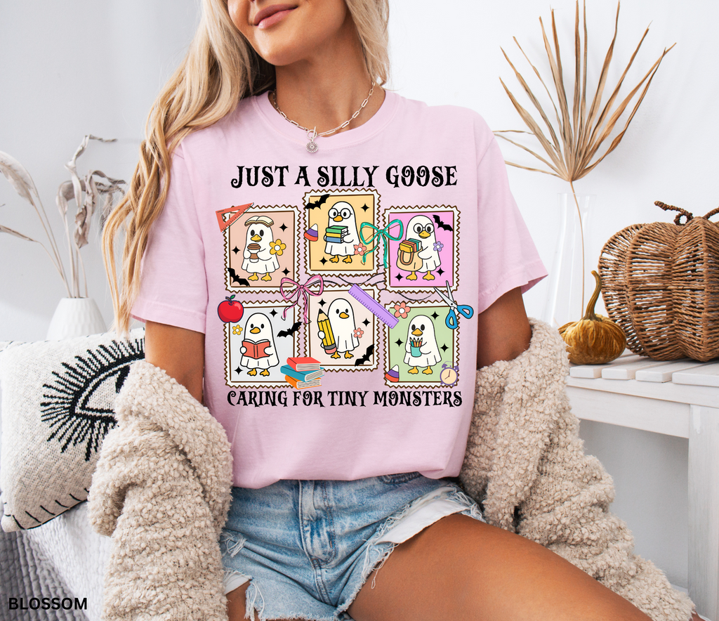 Halloween daycare teacher shirt featuring six cartoon geese in ghost costumes holding books, pencils, and coffee with the phrase “Just a Silly Goose Caring for Tiny Monsters.”