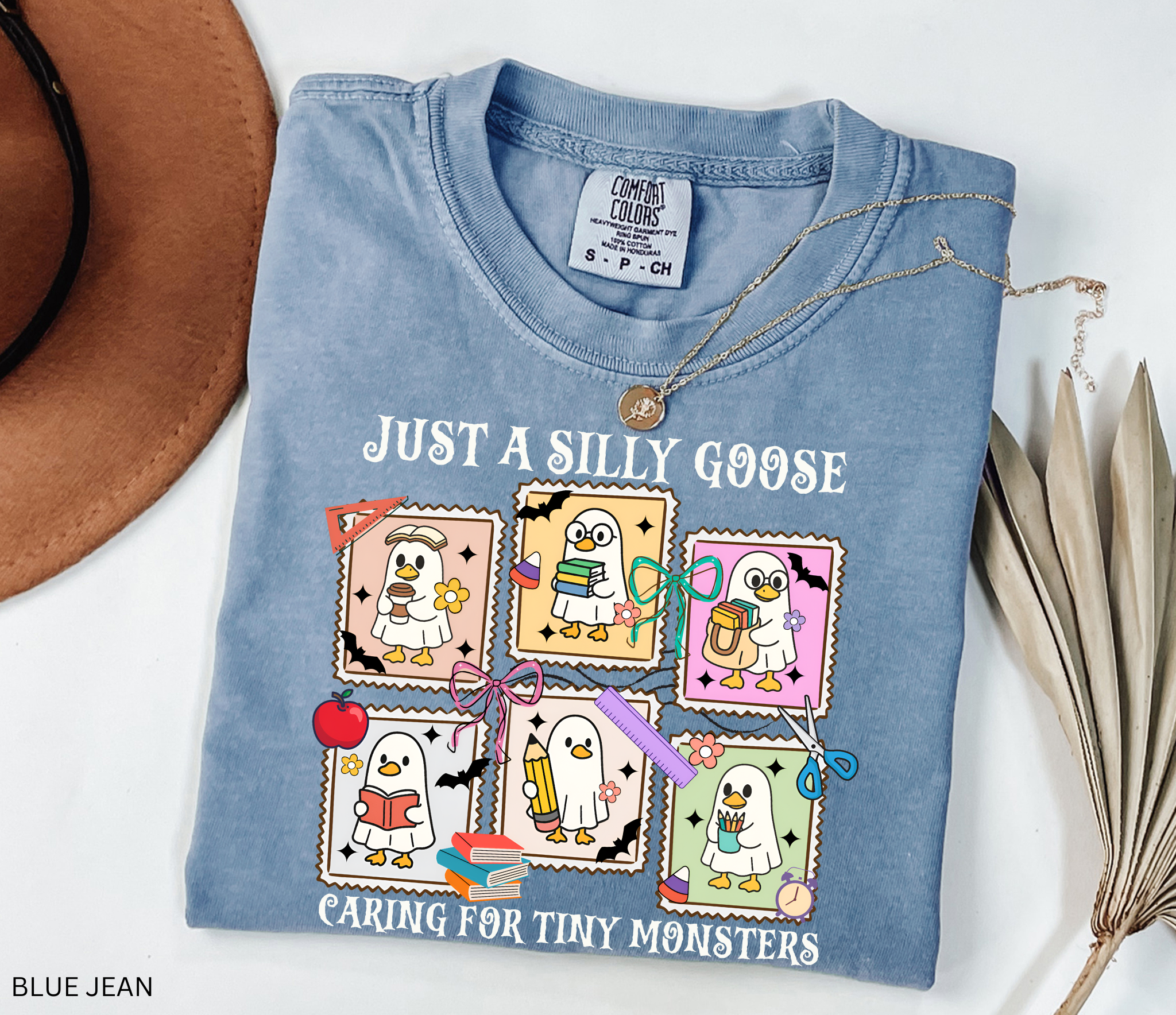 Halloween daycare teacher shirt featuring six cartoon geese in ghost costumes holding books, pencils, and coffee with the phrase “Just a Silly Goose Caring for Tiny Monsters.”
