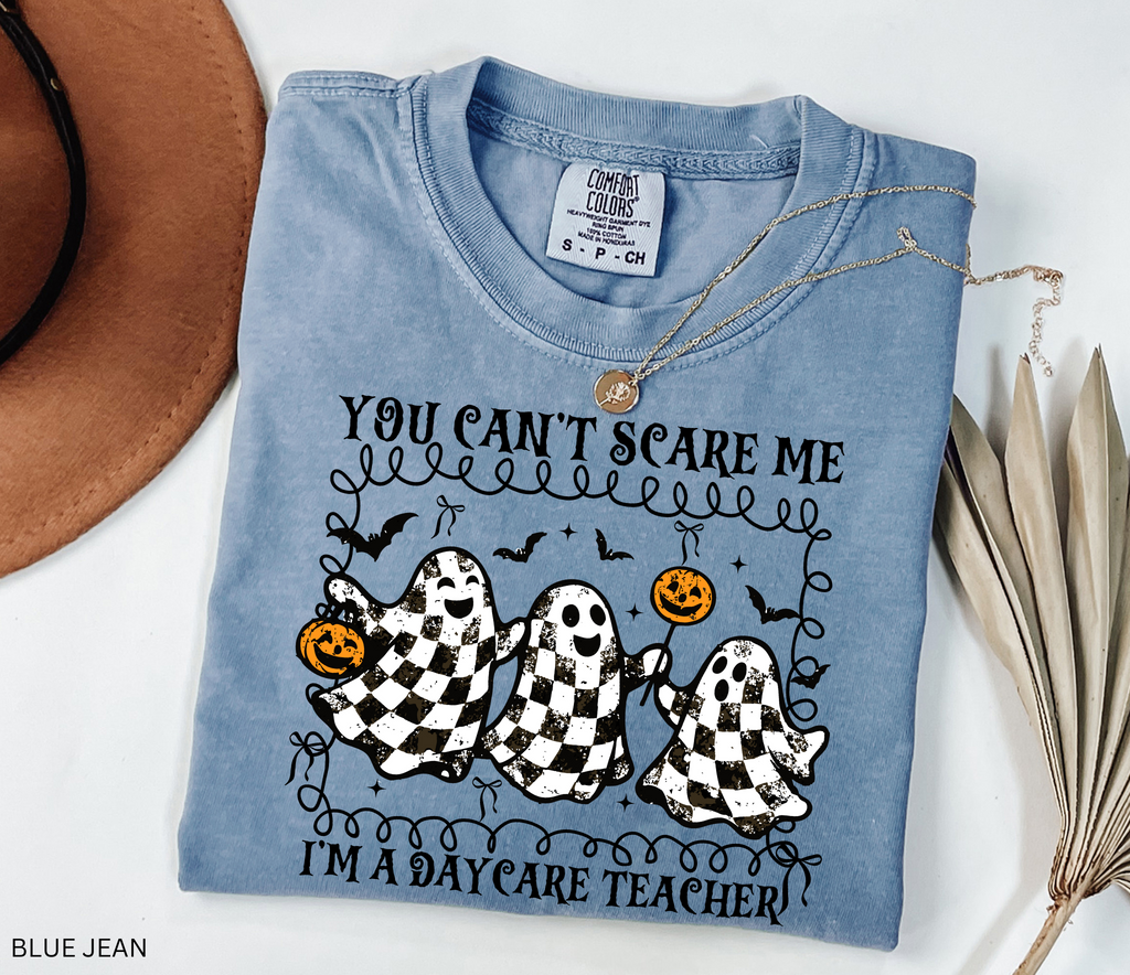 Daycare teacher Halloween shirt with three black and white checkered ghosts holding pumpkins and candy, surrounded by bats in a playful spooky design.