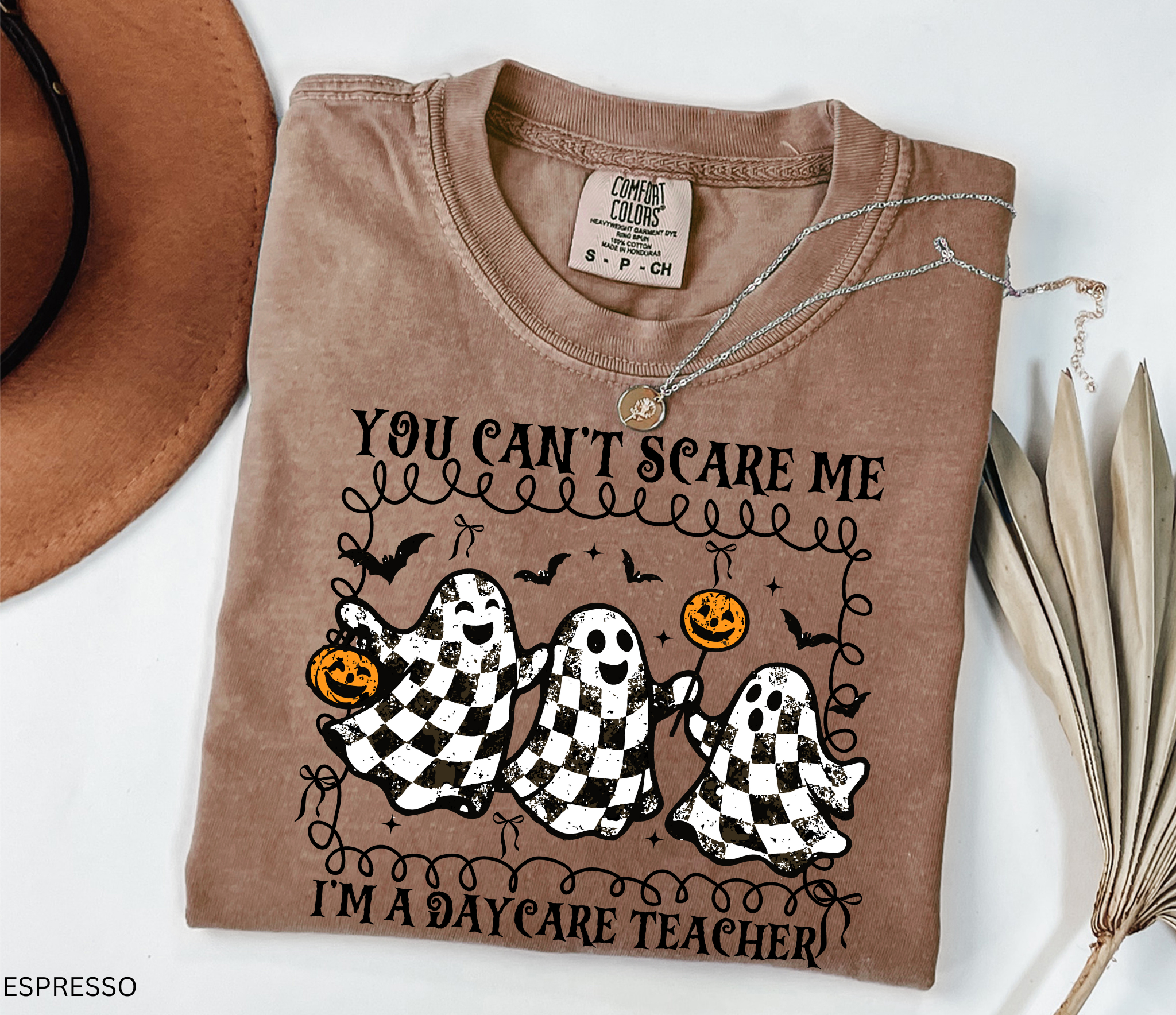 Daycare teacher Halloween shirt with three black and white checkered ghosts holding pumpkins and candy, surrounded by bats in a playful spooky design.