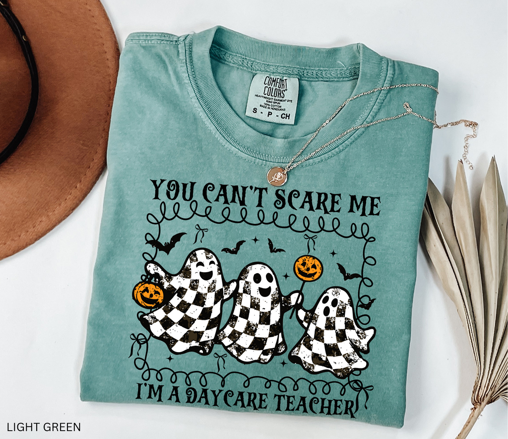 Daycare teacher Halloween shirt with three black and white checkered ghosts holding pumpkins and candy, surrounded by bats in a playful spooky design.