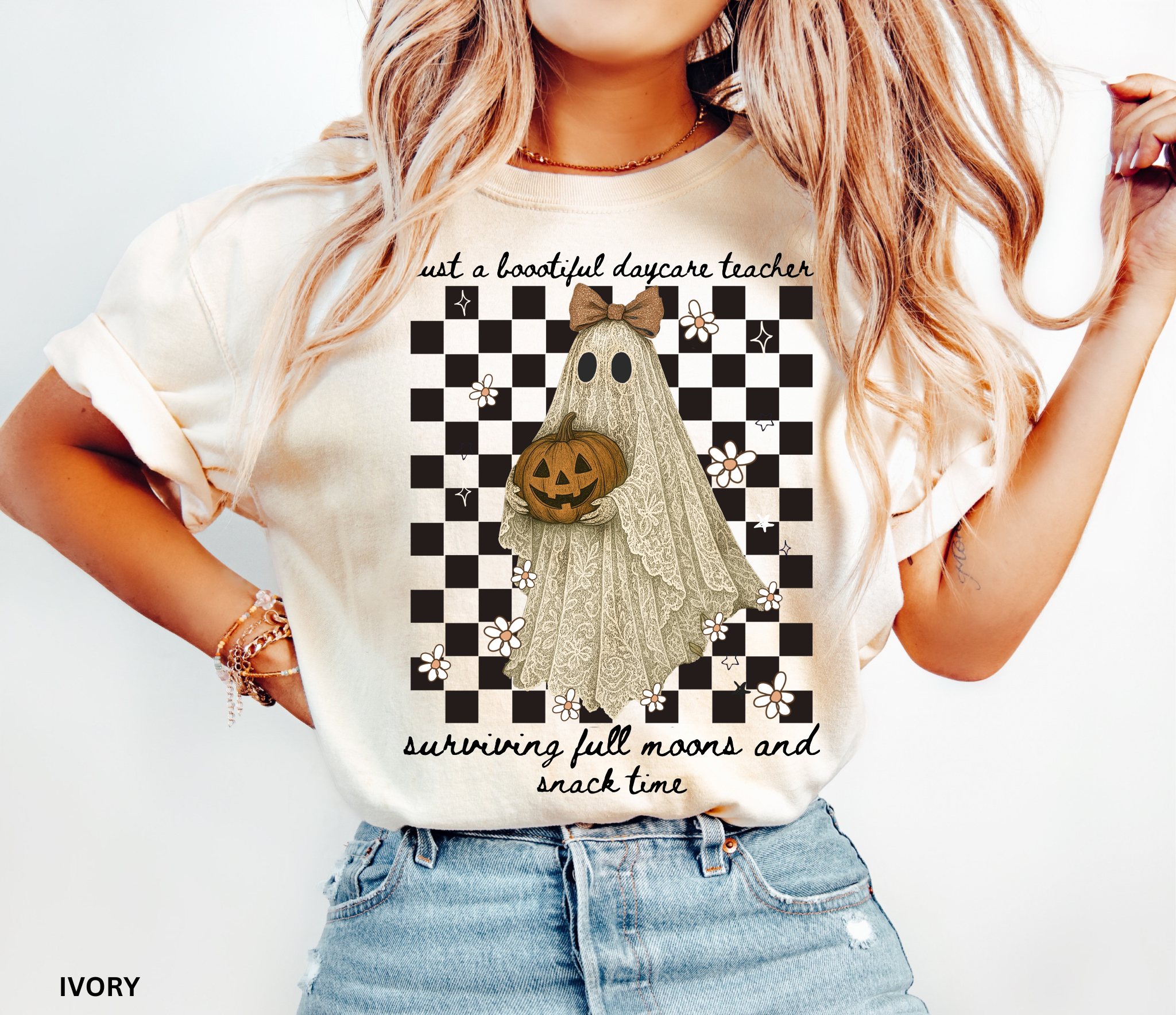 Daycare teacher Halloween shirt featuring a lace-patterned ghost holding a jack-o’-lantern pumpkin, wearing a bow, with flowers and stars on a checkered background.