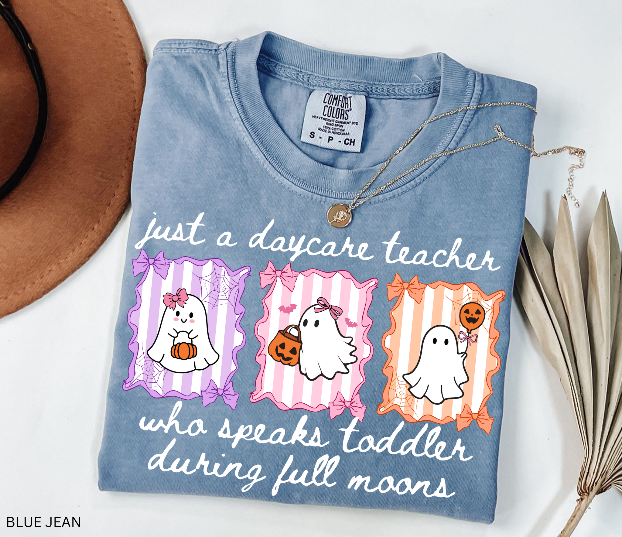 Daycare teacher Halloween shirt featuring three pastel ghosts with bows, pumpkins, and a candy bucket on striped backgrounds with spiderweb and bow accents.