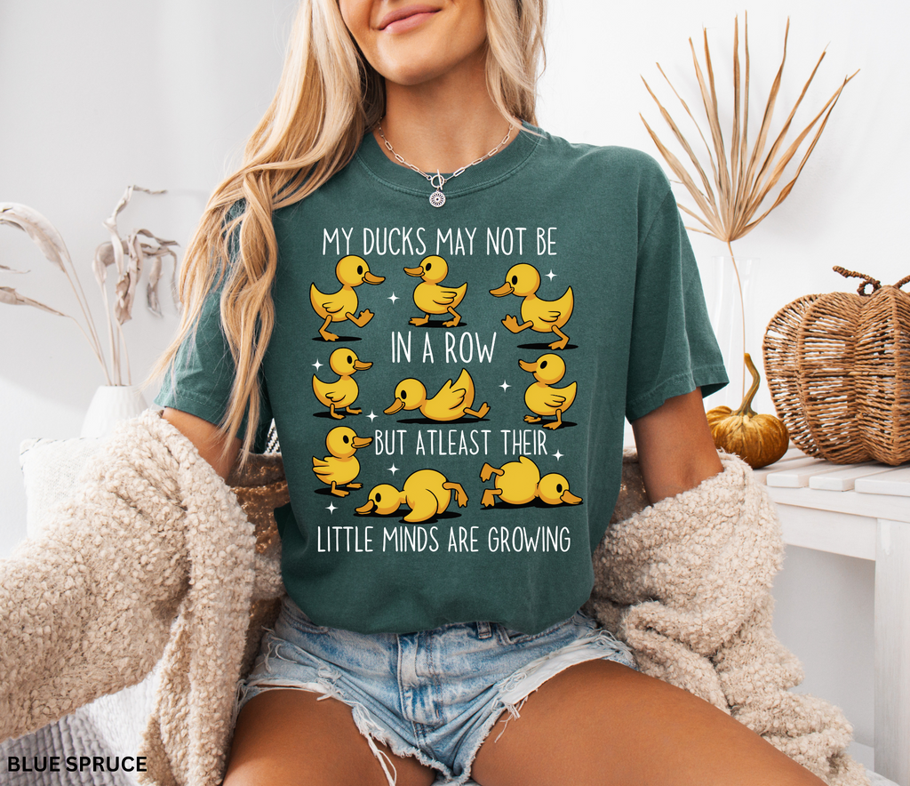 Daycare teacher shirt with cartoon yellow ducks in playful poses and the phrase “My Ducks May Not Be in a Row but at Least Their Little Minds Are Growing.”
