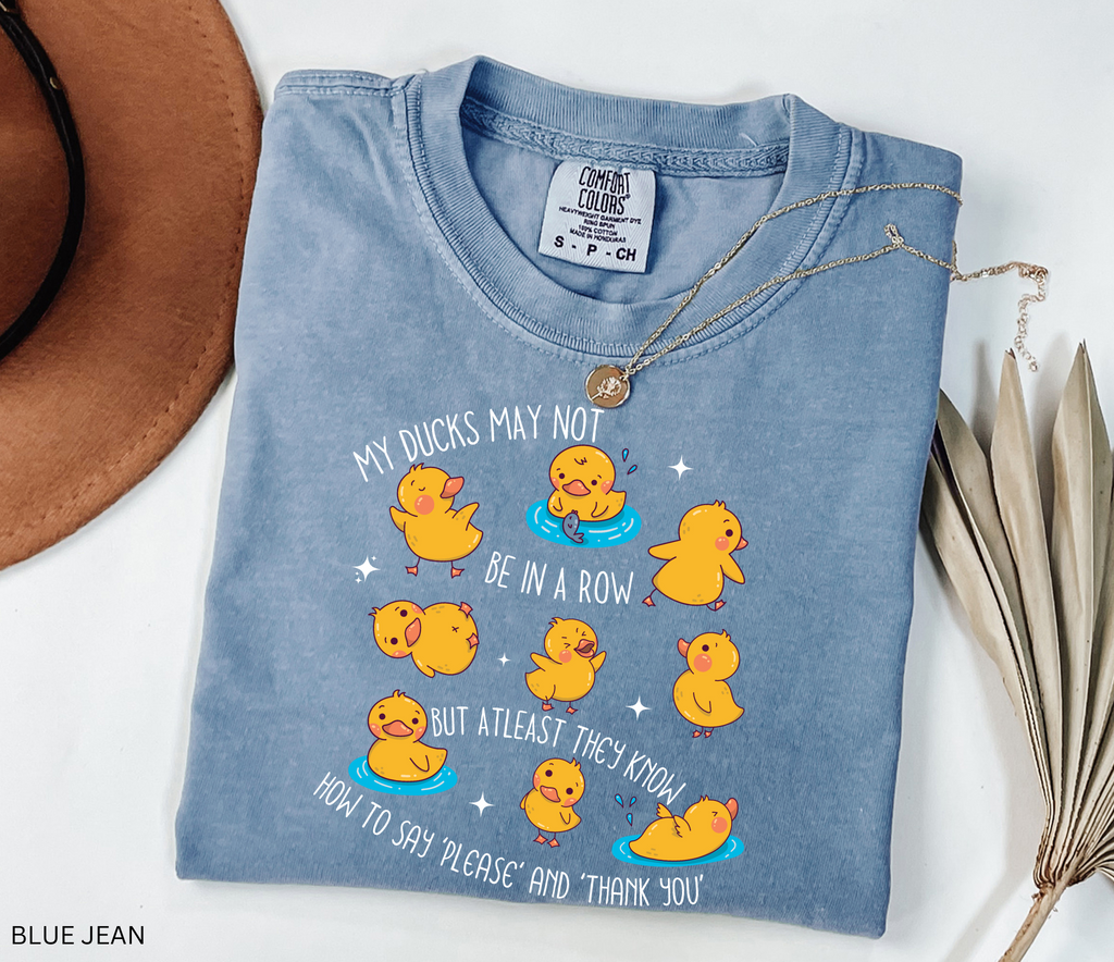 Funny daycare teacher shirt with cartoon yellow ducks in playful poses, water puddles, and the phrase “My Ducks May Not Be in a Row but at Least They Know How to Say Please and Thank You.”