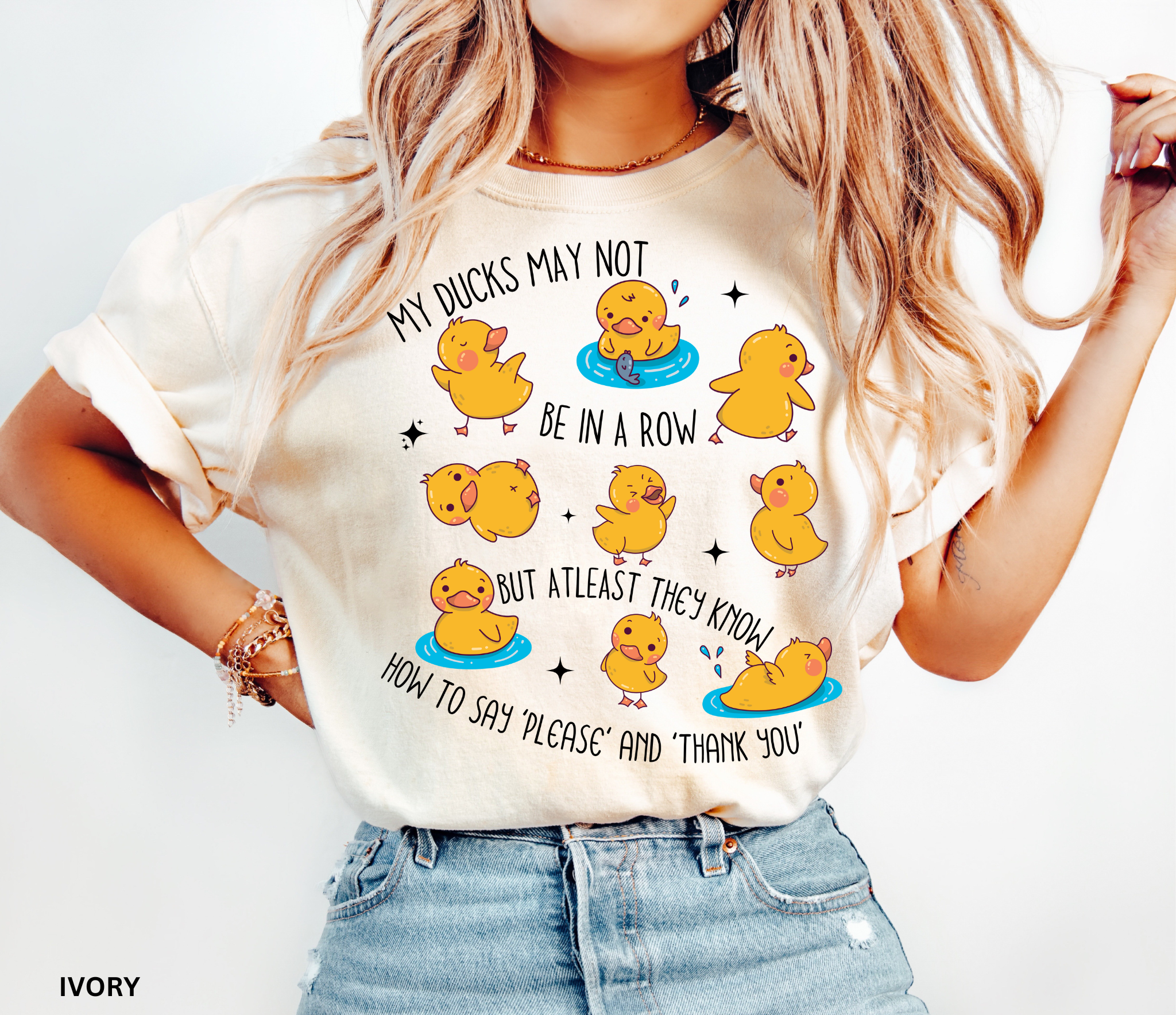 Funny daycare teacher shirt with cartoon yellow ducks in playful poses, water puddles, and the phrase “My Ducks May Not Be in a Row but at Least They Know How to Say Please and Thank You.”
