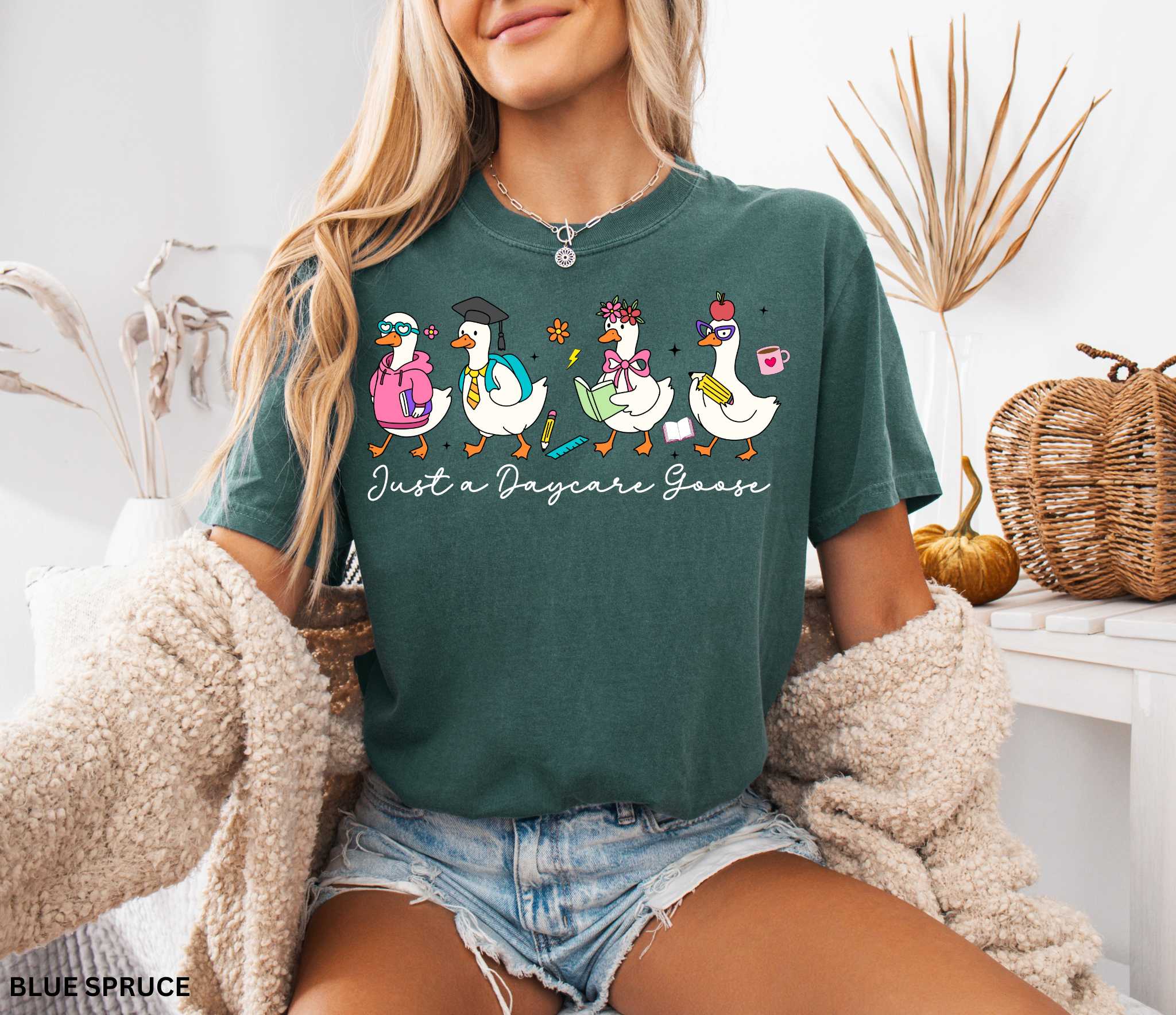 Funny daycare teacher shirt with four cartoon geese dressed as students and teachers, holding books and supplies, with the phrase “Just a Daycare Goose.”