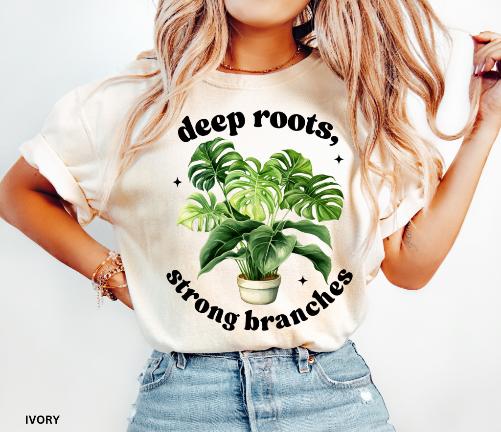 ivory shirt with a large green monstera plant in a pot and the inspirational phrase Deep Roots, Strong Branches in white text.