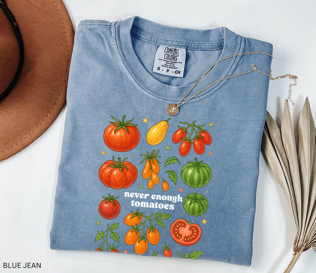 Watercolor-style illustration of different tomato varieties with the phrase “never enough tomatoes” on a cottagecore garden t-shirt.