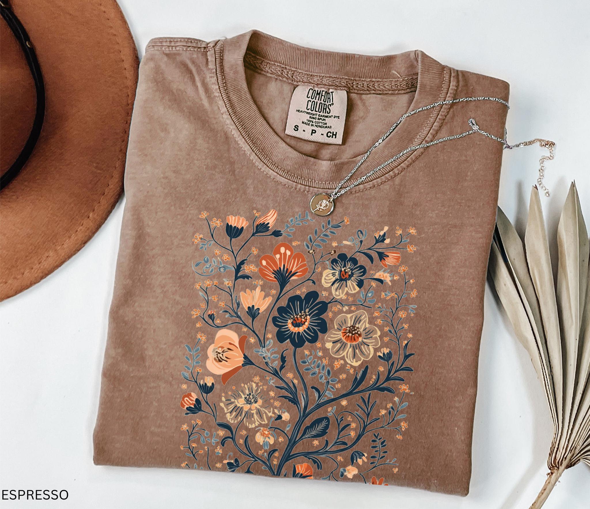 Vintage folk-art style floral design with detailed wildflowers in earthy tones printed on a cottagecore-inspired t-shirt.