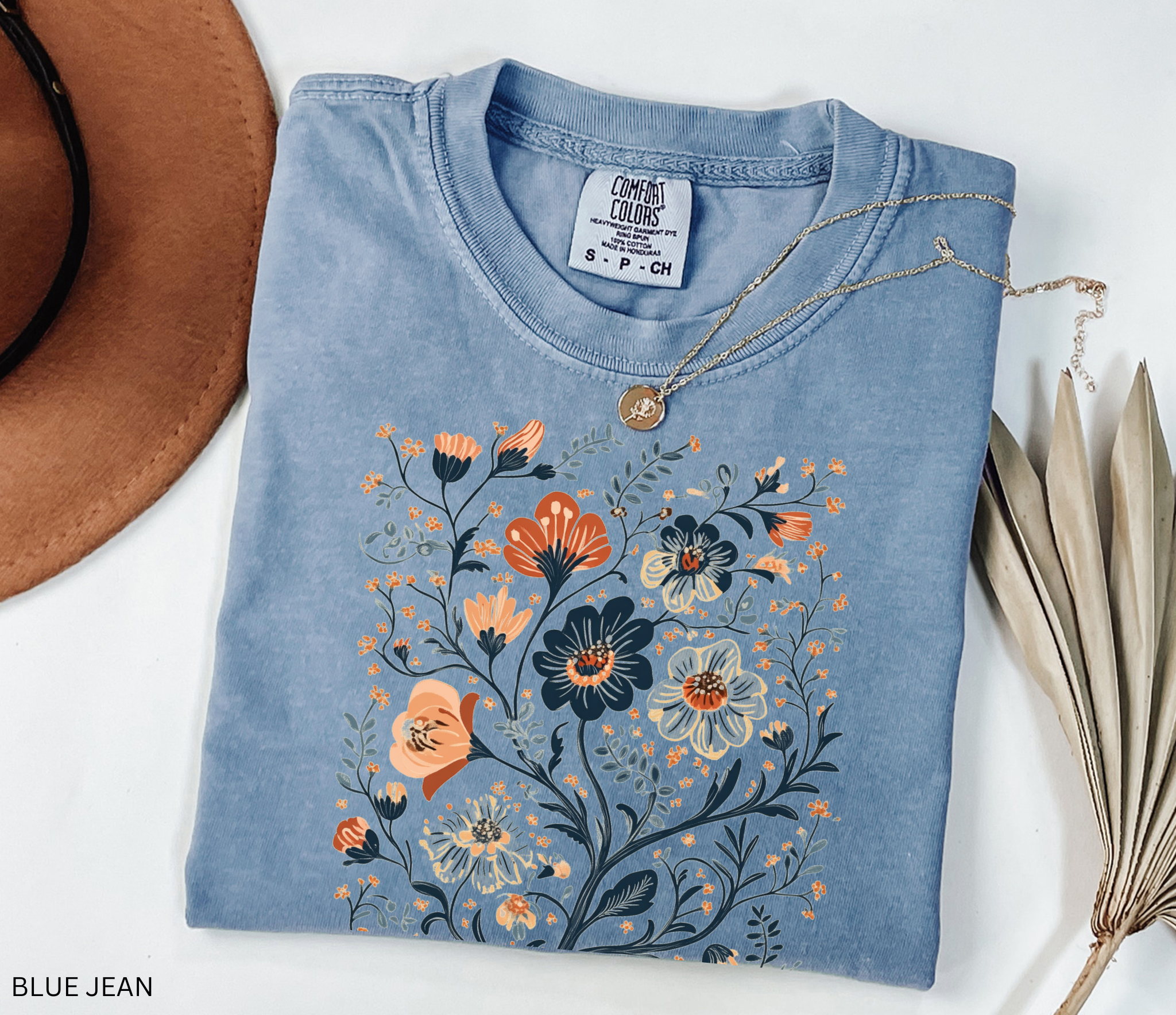 Vintage folk-art style floral design with detailed wildflowers in earthy tones printed on a cottagecore-inspired t-shirt.