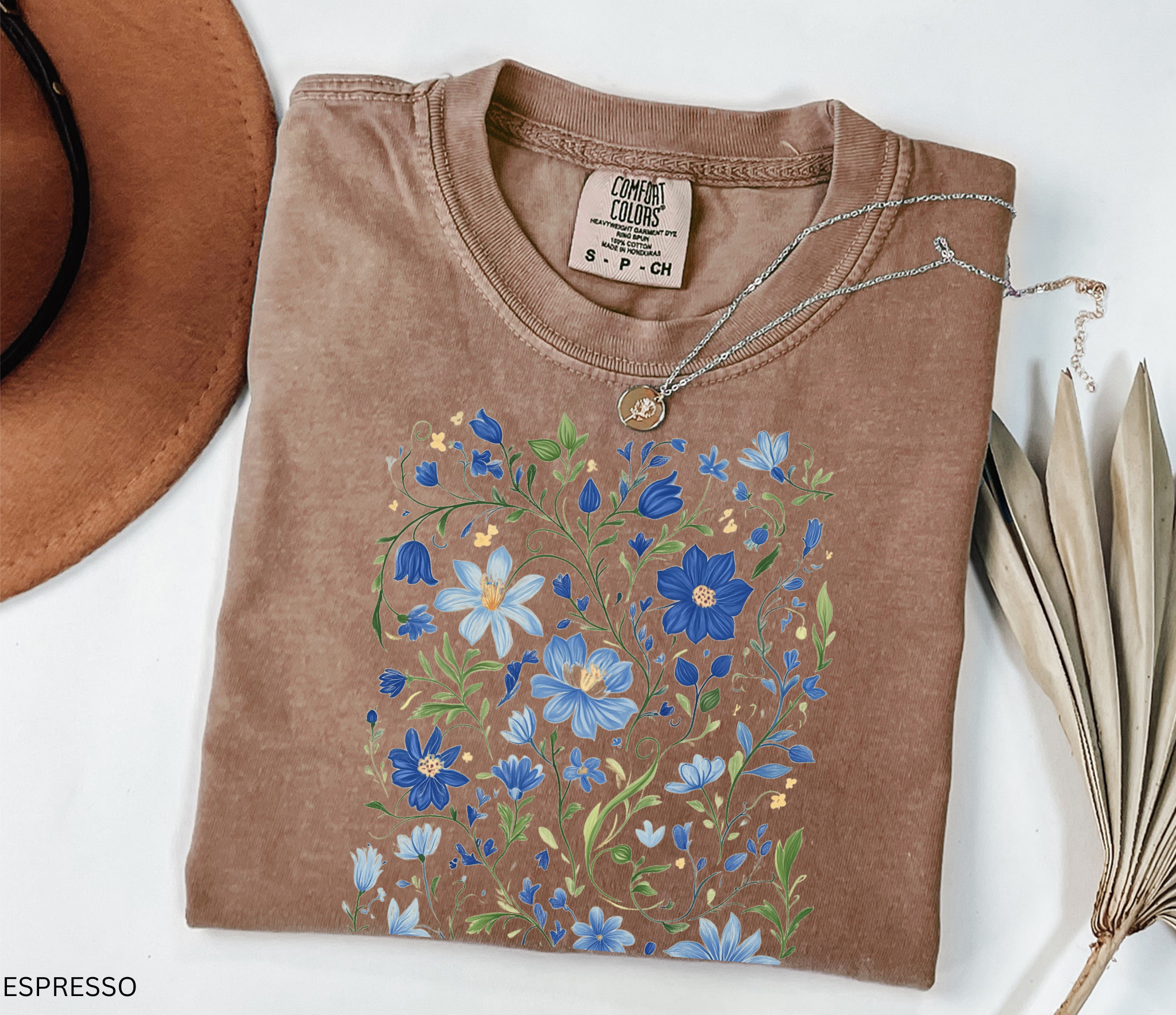 Detailed folk-art style design of blue wildflowers and green vines, printed on a cottagecore floral t-shirt.