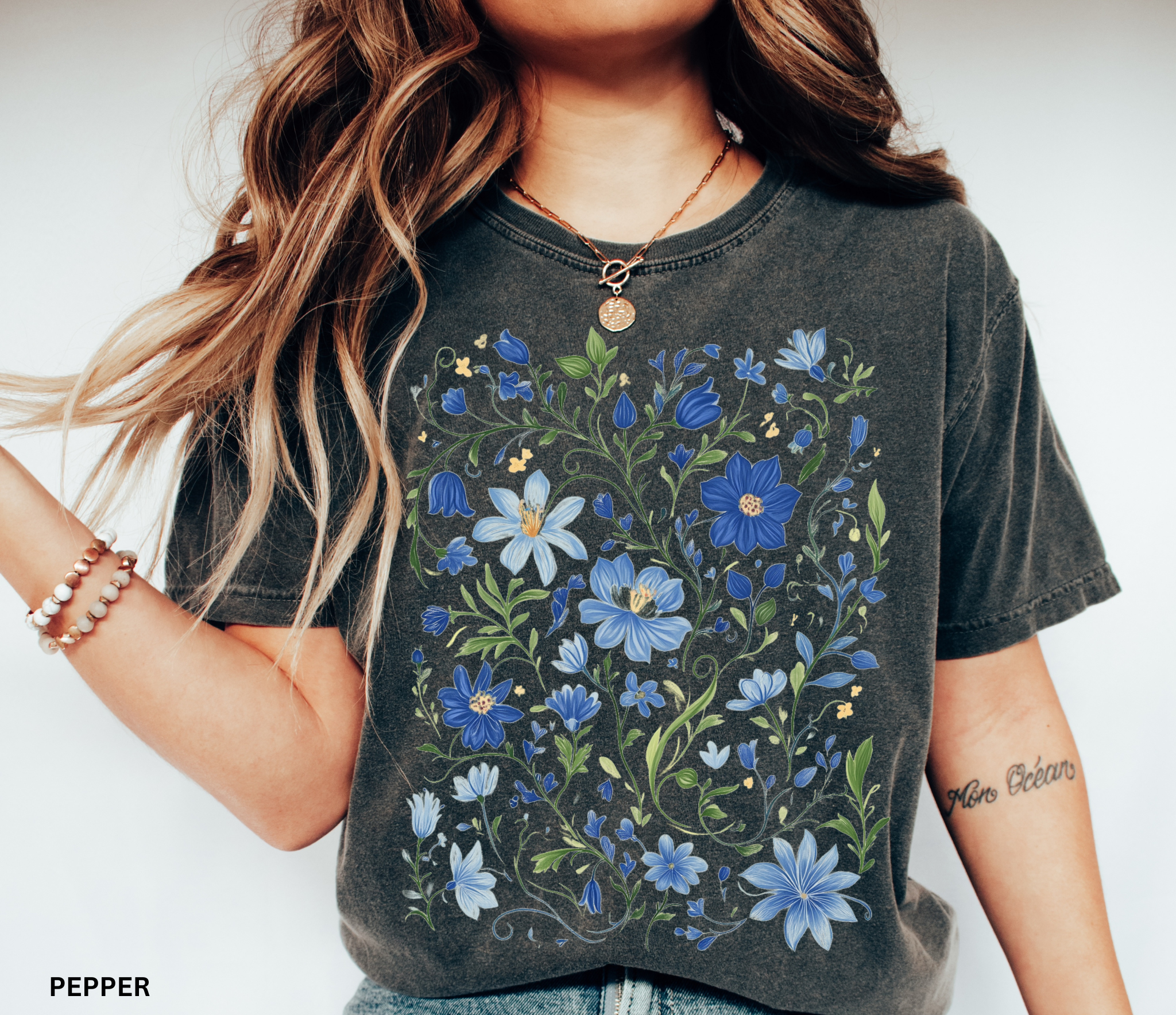 Detailed folk-art style design of blue wildflowers and green vines, printed on a cottagecore floral t-shirt.