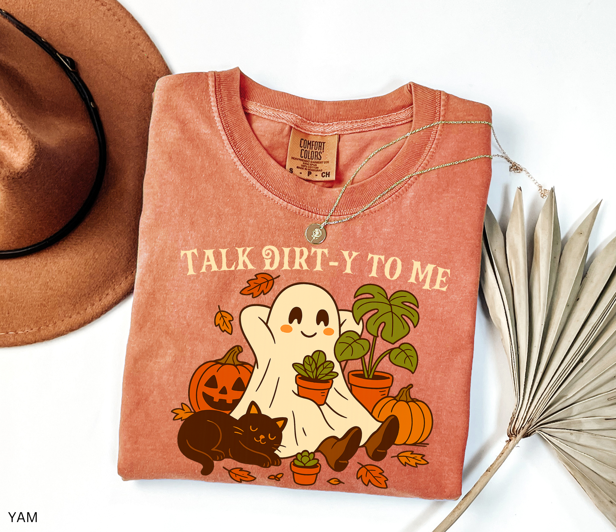 Halloween shirt design featuring a happy ghost holding a potted plant, surrounded by pumpkins, autumn leaves, a monstera, and a cozy black cat with the phrase “Talk Dirt-y to Me.”