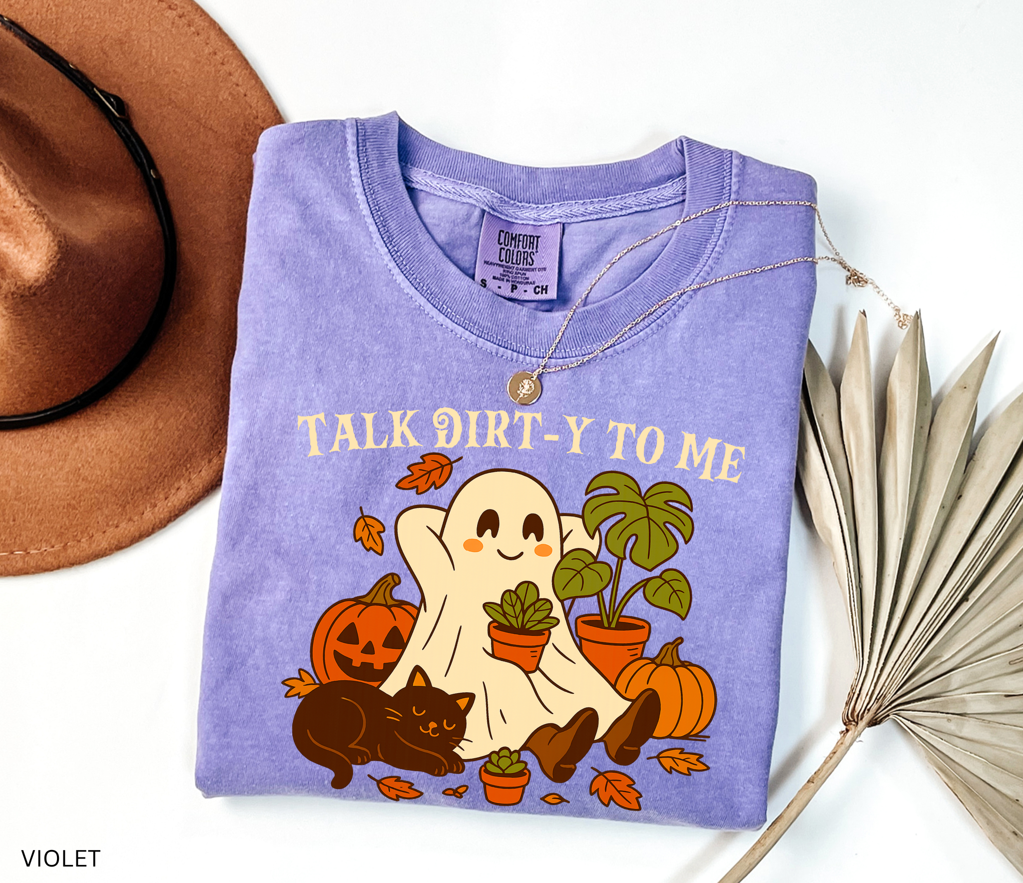 Halloween shirt design featuring a happy ghost holding a potted plant, surrounded by pumpkins, autumn leaves, a monstera, and a cozy black cat with the phrase “Talk Dirt-y to Me.”