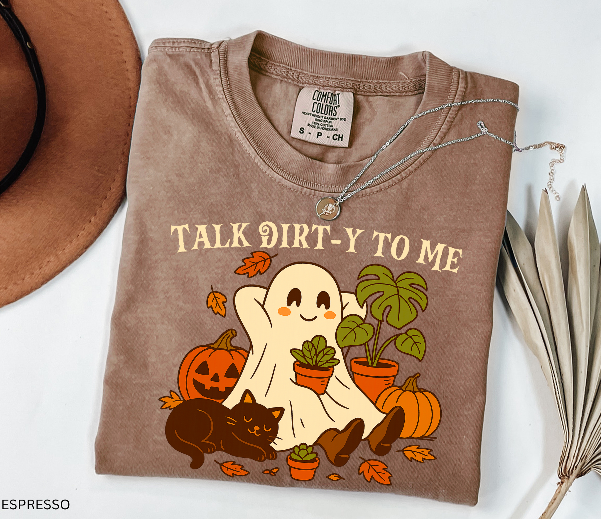 Halloween shirt design featuring a happy ghost holding a potted plant, surrounded by pumpkins, autumn leaves, a monstera, and a cozy black cat with the phrase “Talk Dirt-y to Me.”