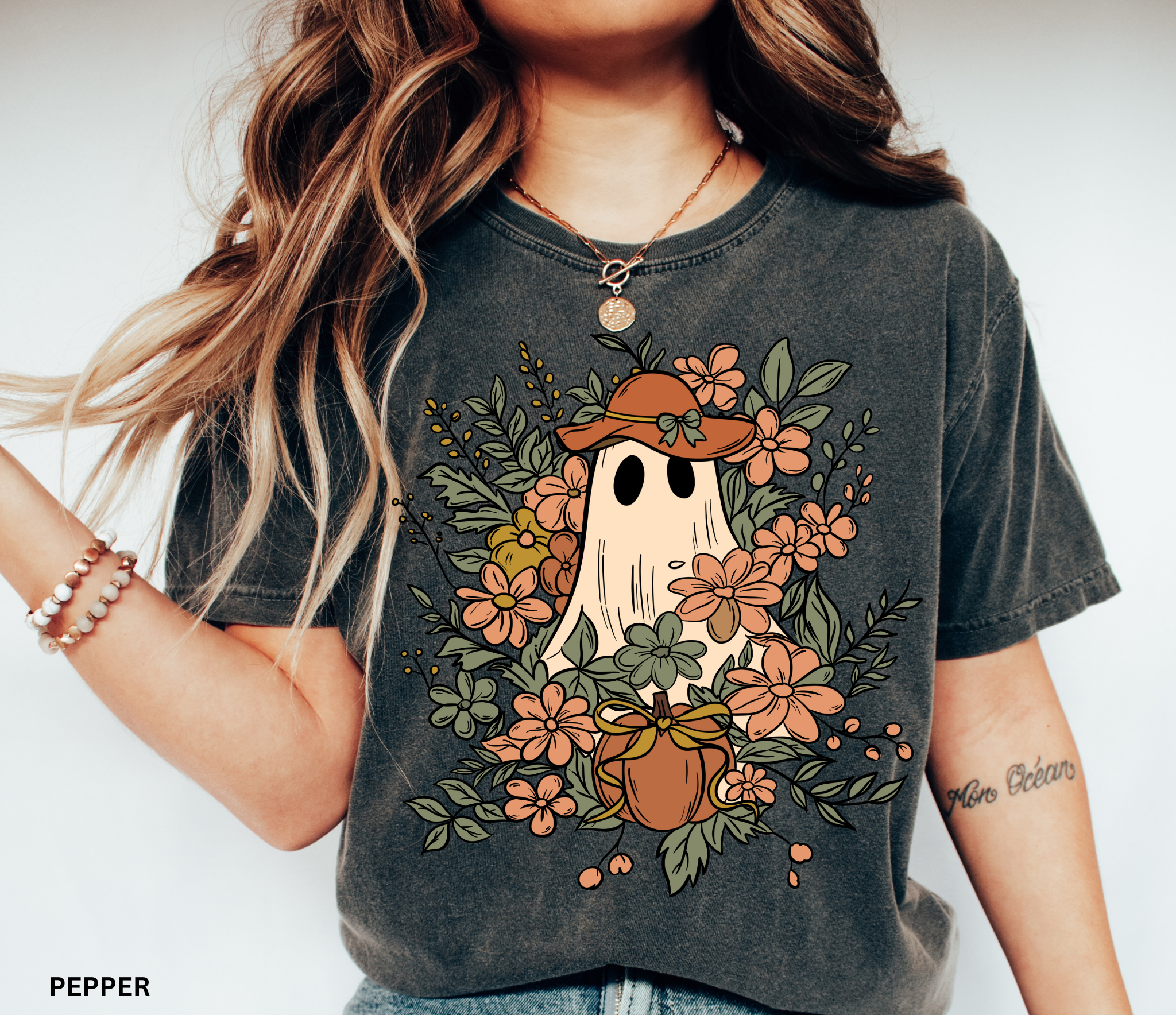 Halloween shirt featuring a ghost in a wide-brimmed hat surrounded by orange flowers, greenery, and a pumpkin with a bow – a spooky cottagecore gardening design.