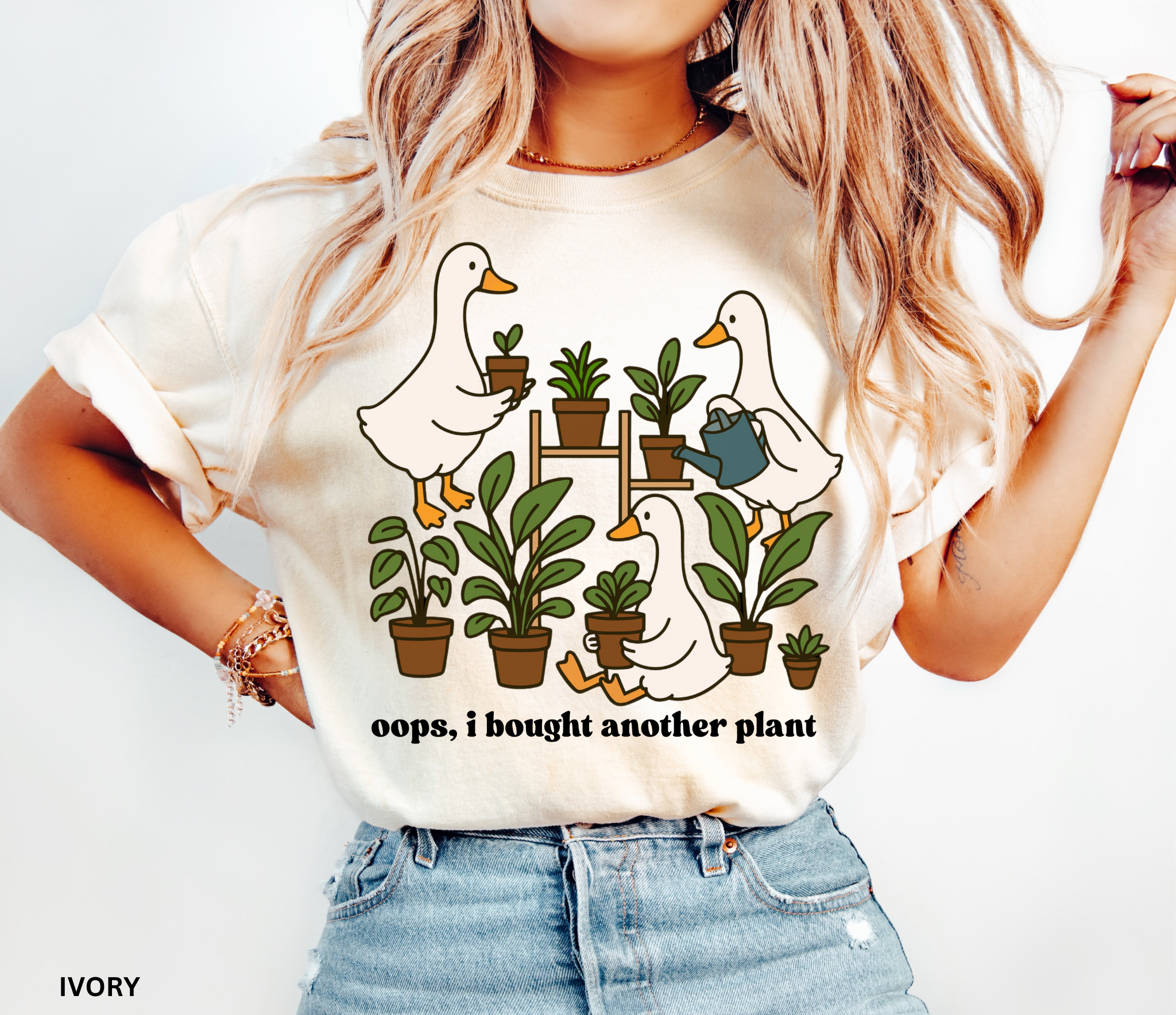 Funny gardening shirt with geese holding potted plants and watering cans, surrounded by greenery, with the phrase “Oops, I Bought Another Plant.”