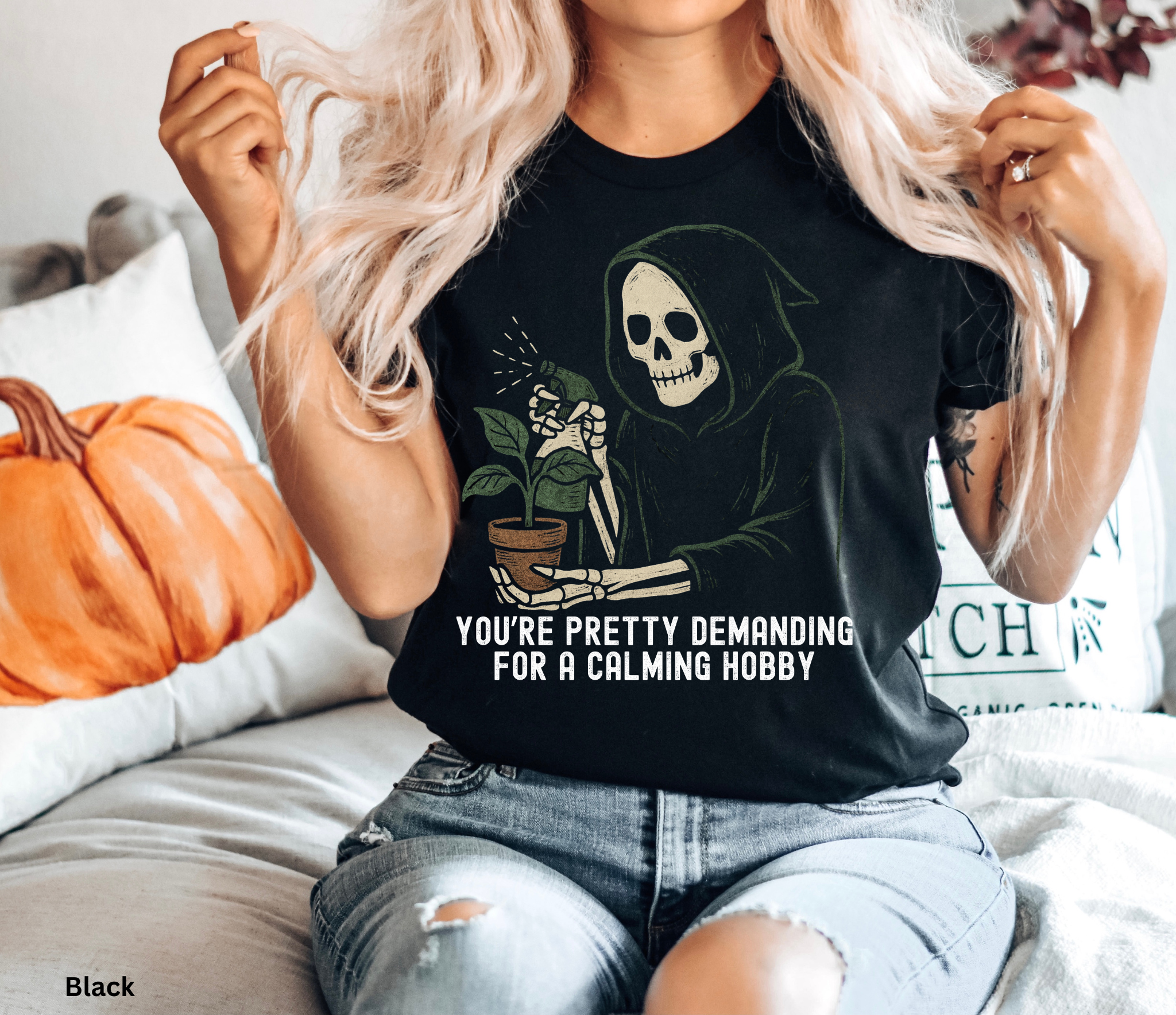 Halloween-style shirt featuring a grim reaper skeleton watering a potted plant with the phrase “You’re Pretty Demanding for a Calming Hobby.”