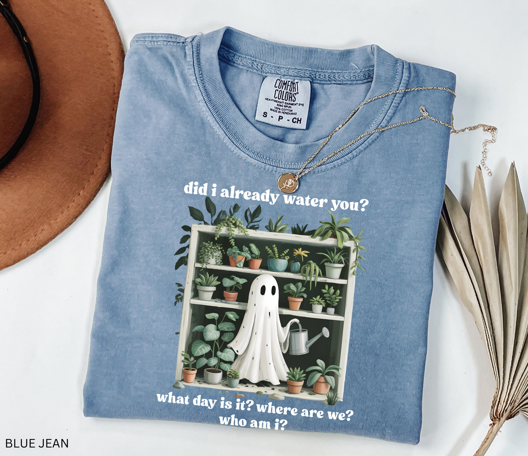 Funny gardening shirt featuring a ghost holding a watering can in front of a shelf full of houseplants with the phrase “Did I already water you? What day is it? Where are we? Who am I?”