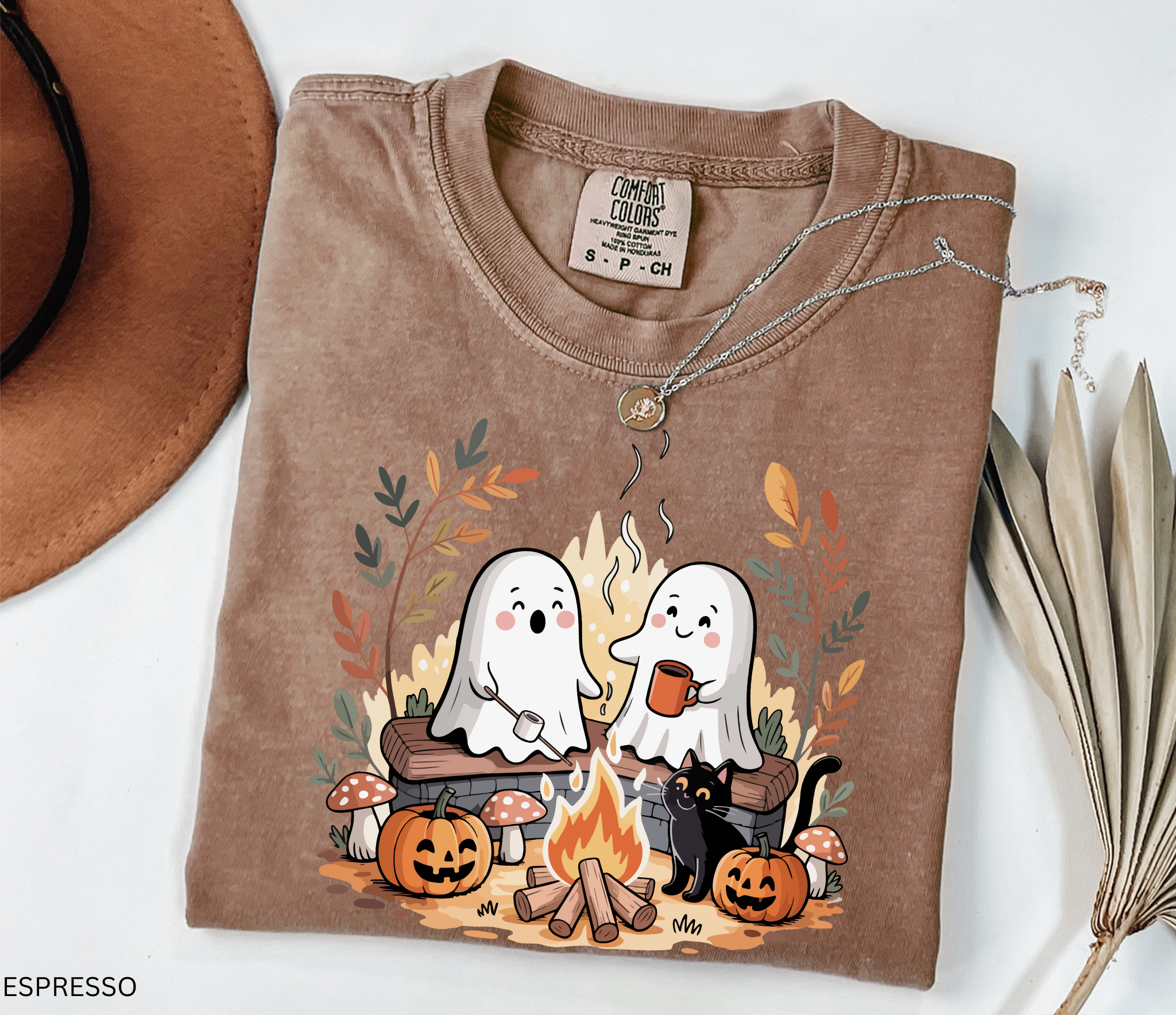 Halloween shirt design featuring two cute ghosts by a campfire, one roasting marshmallows, one holding cocoa, with pumpkins, mushrooms, fall leaves, and a black cat.